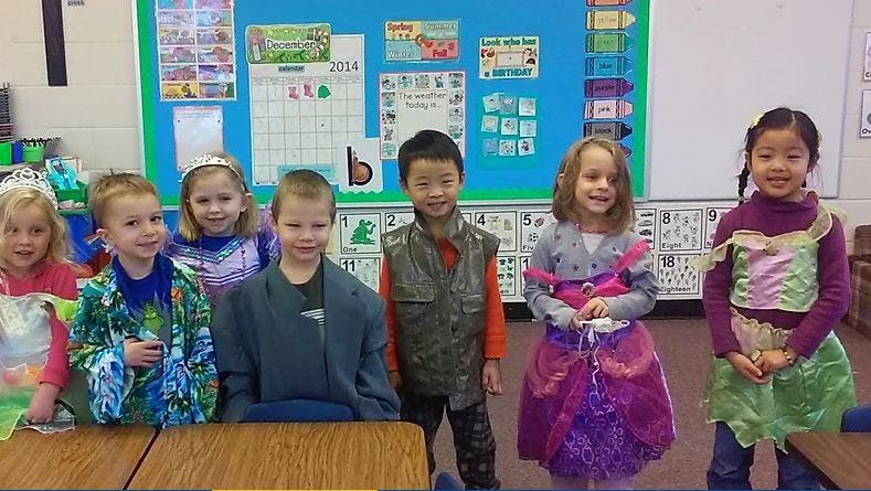 Six children in costumes in a classroom