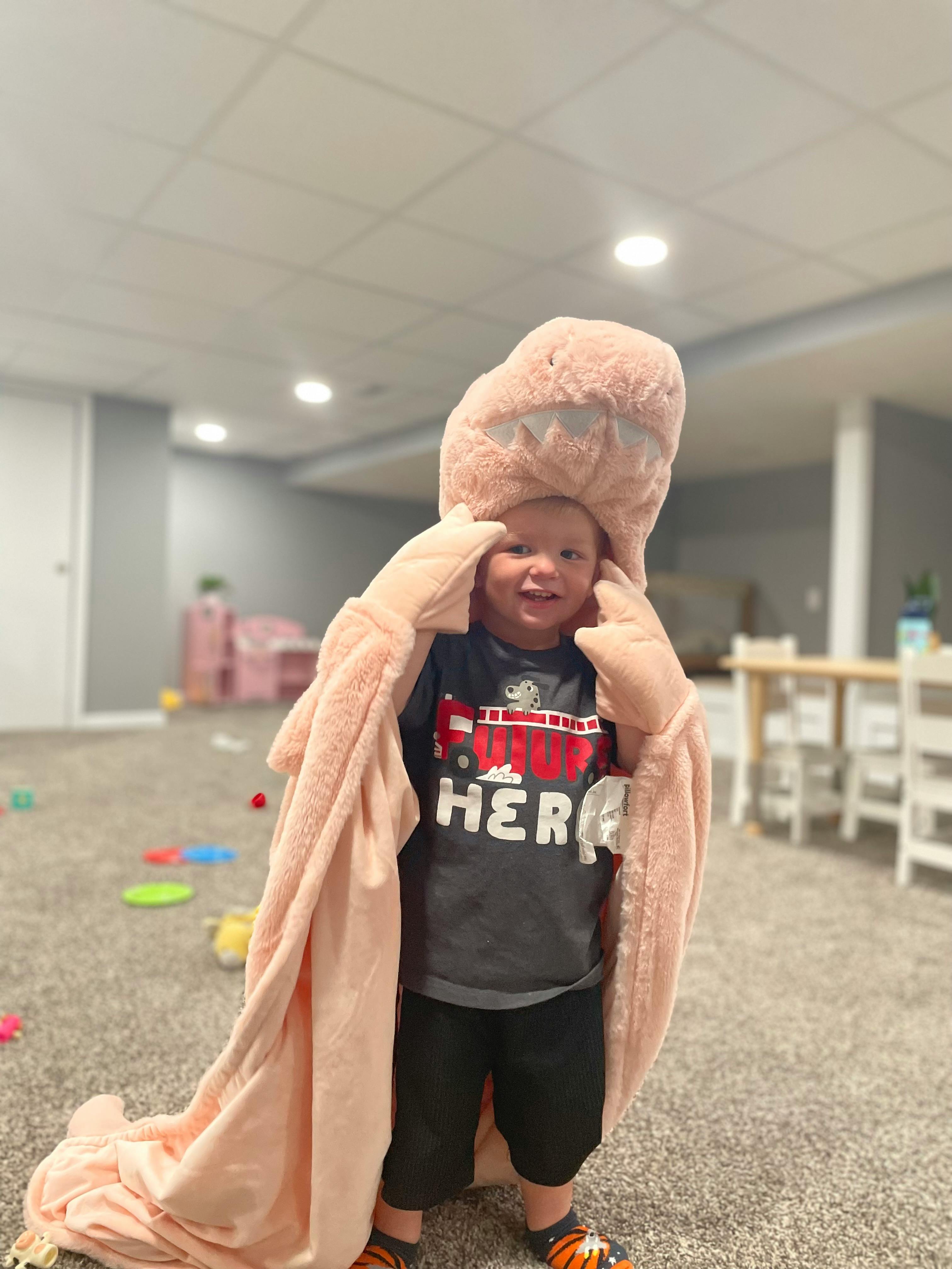 Child wearing a large pink blanket over their head and shoulders