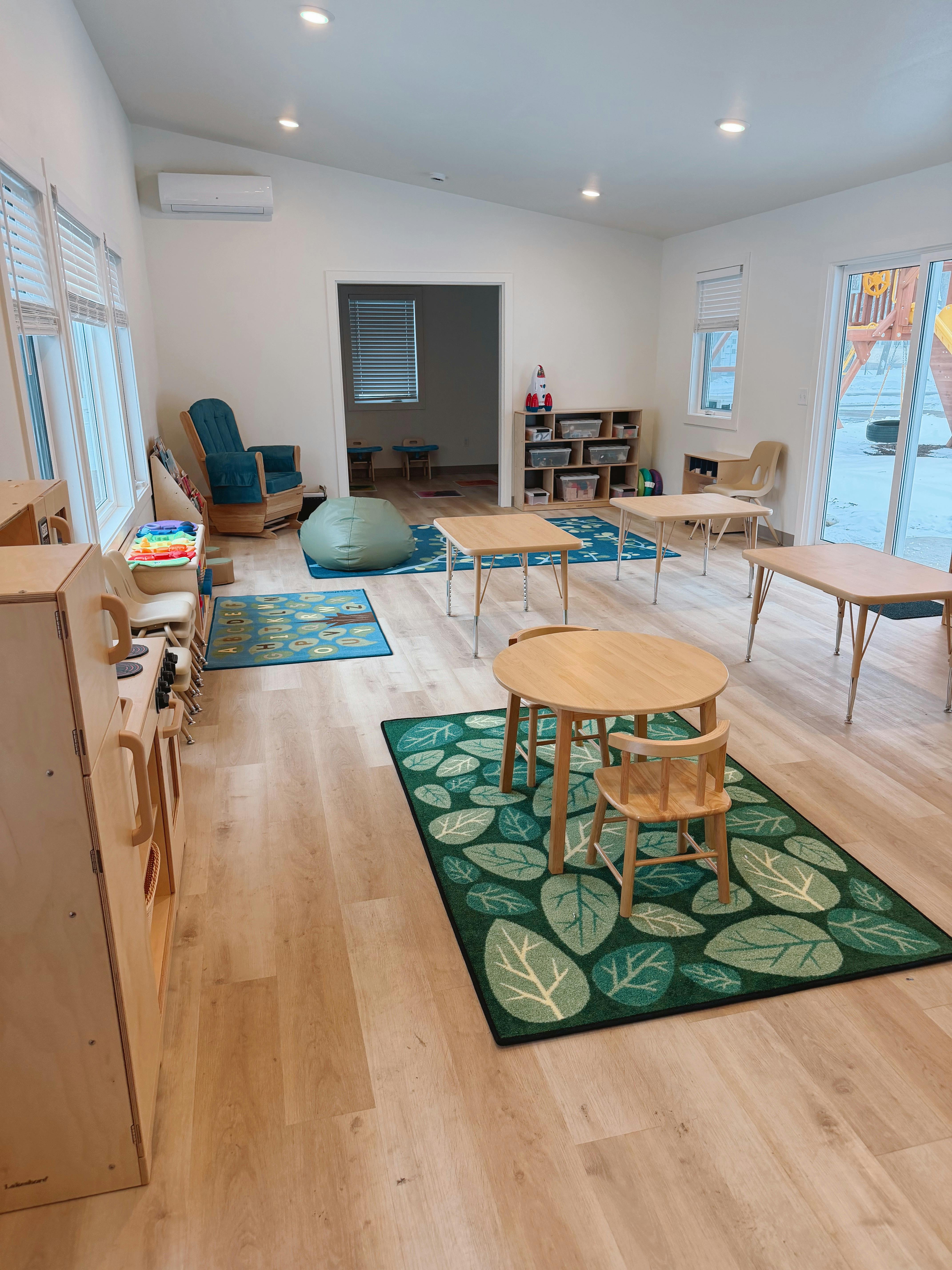A playroom or classroom with child-sized tables, chairs, and rugs