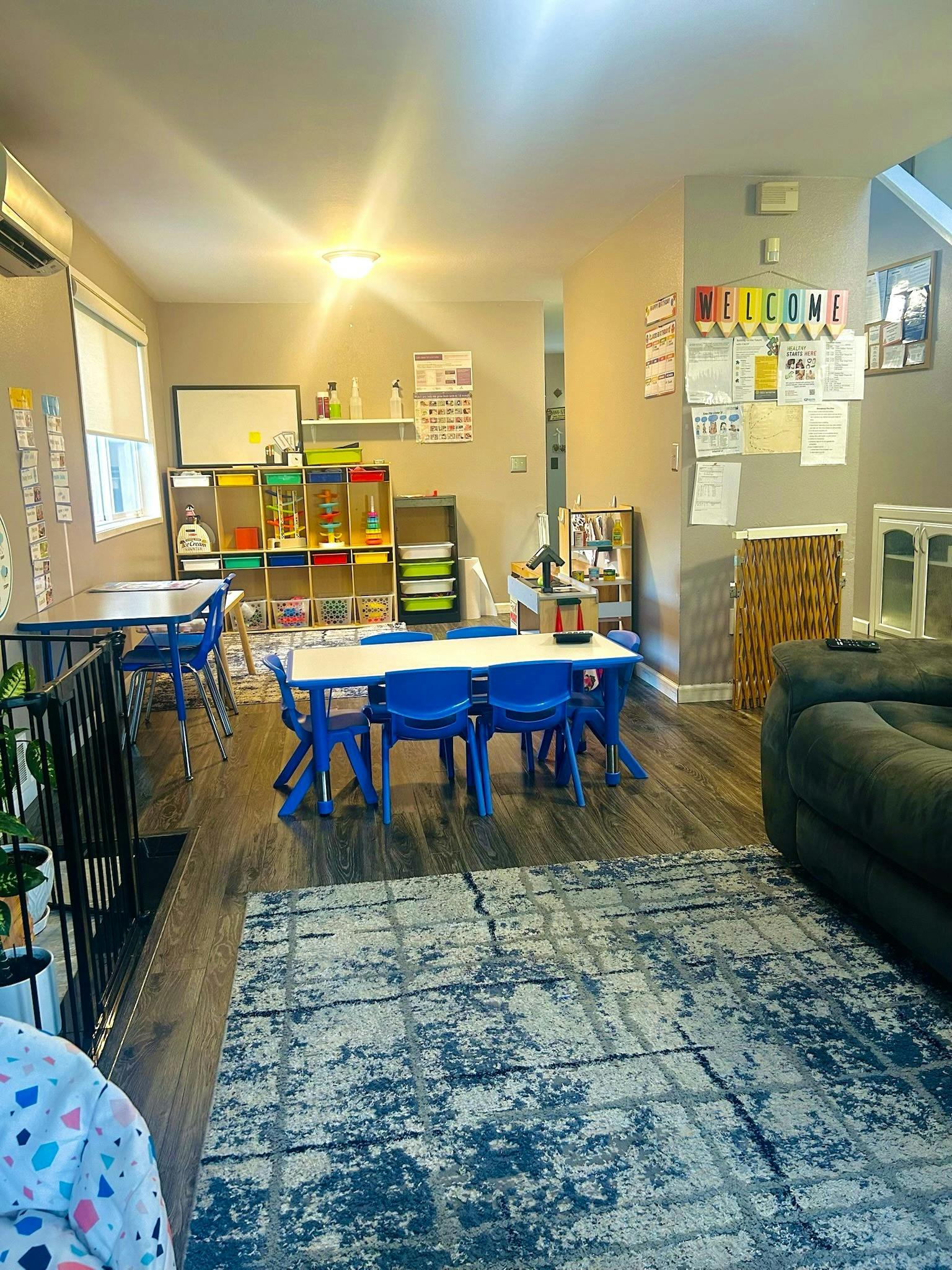 Classroom with small tables and chairs, storage shelves, and a welcome sign