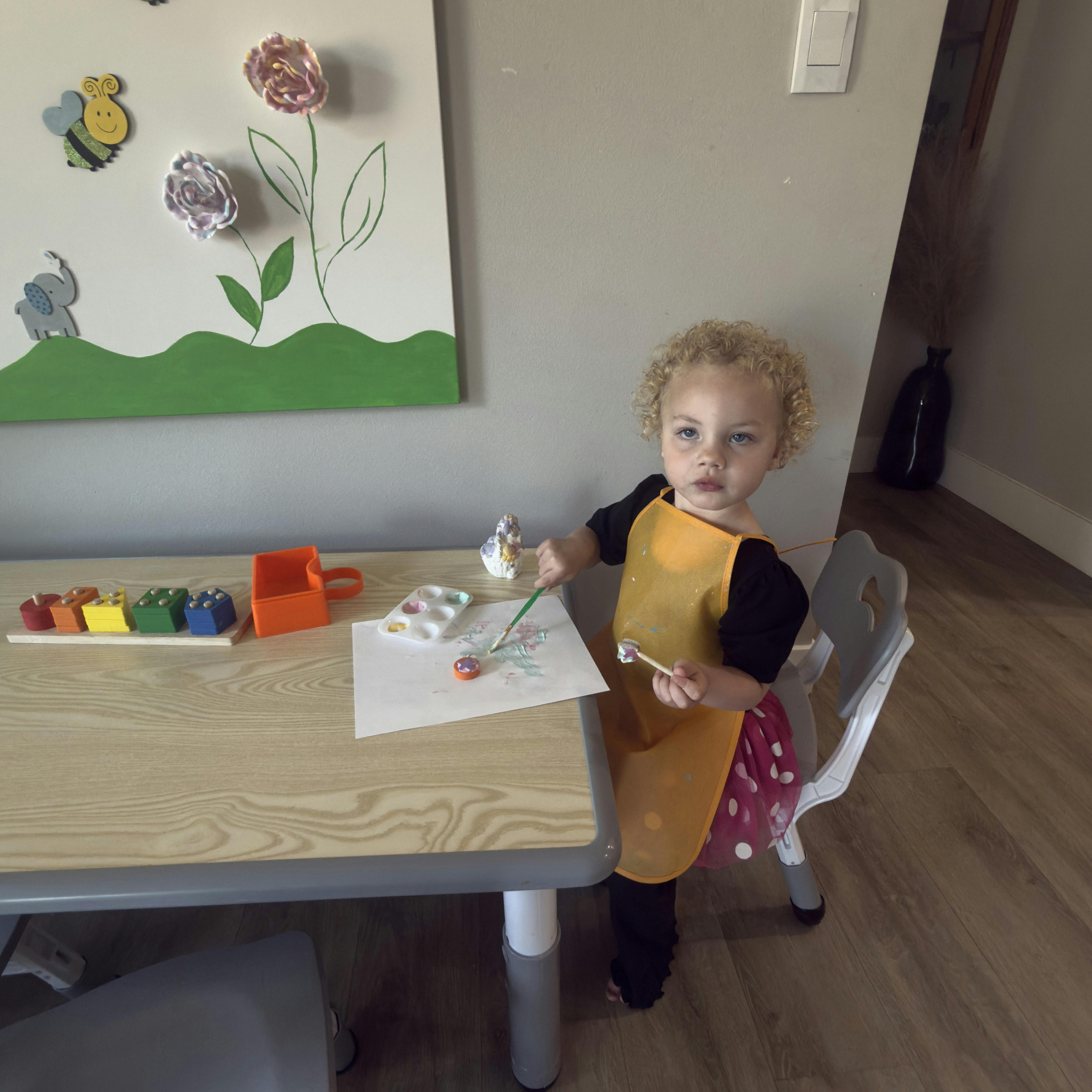 Child painting on paper at a small table