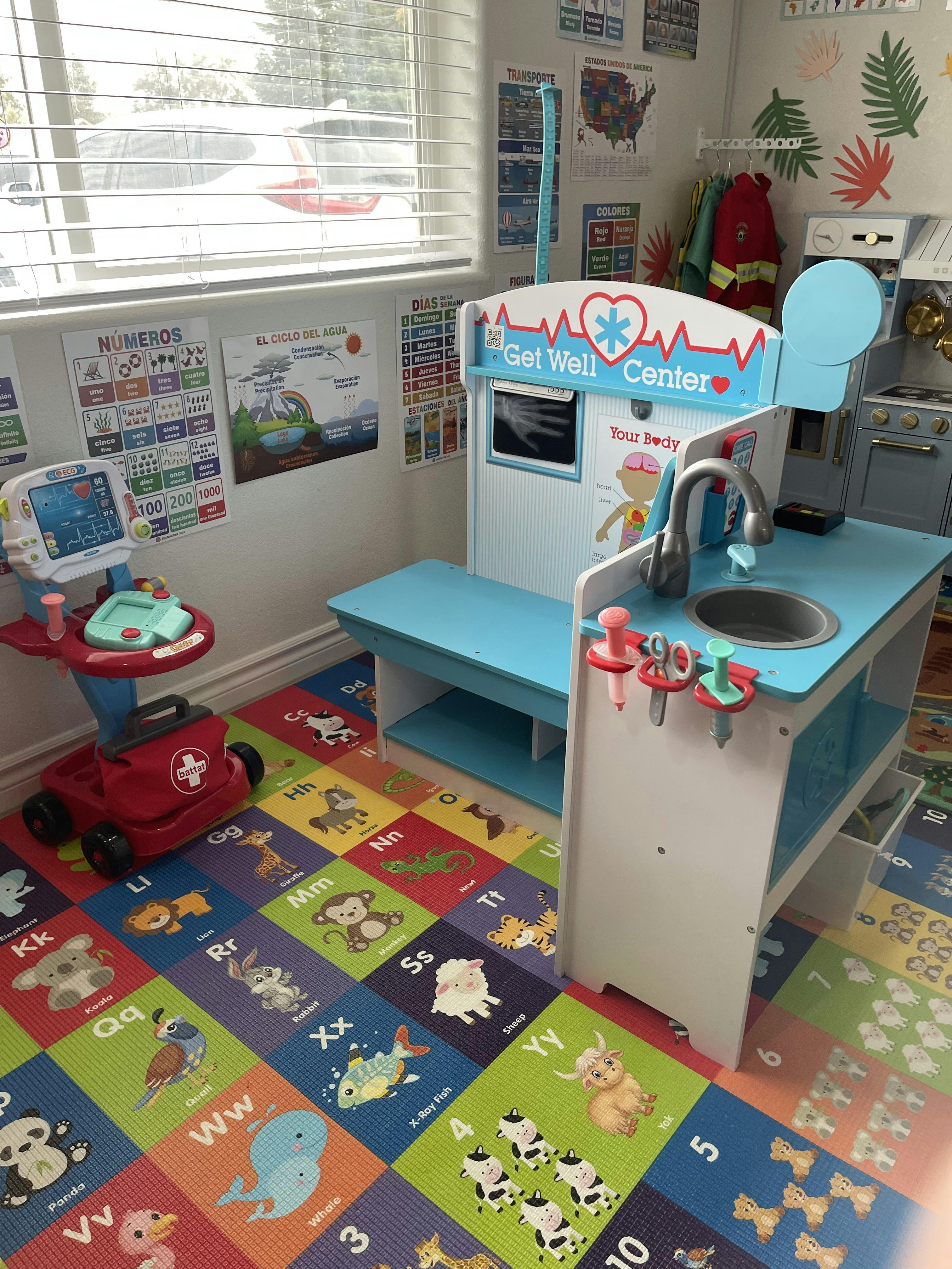 Playroom with a toy doctor's office and kitchen set on an alphabet mat