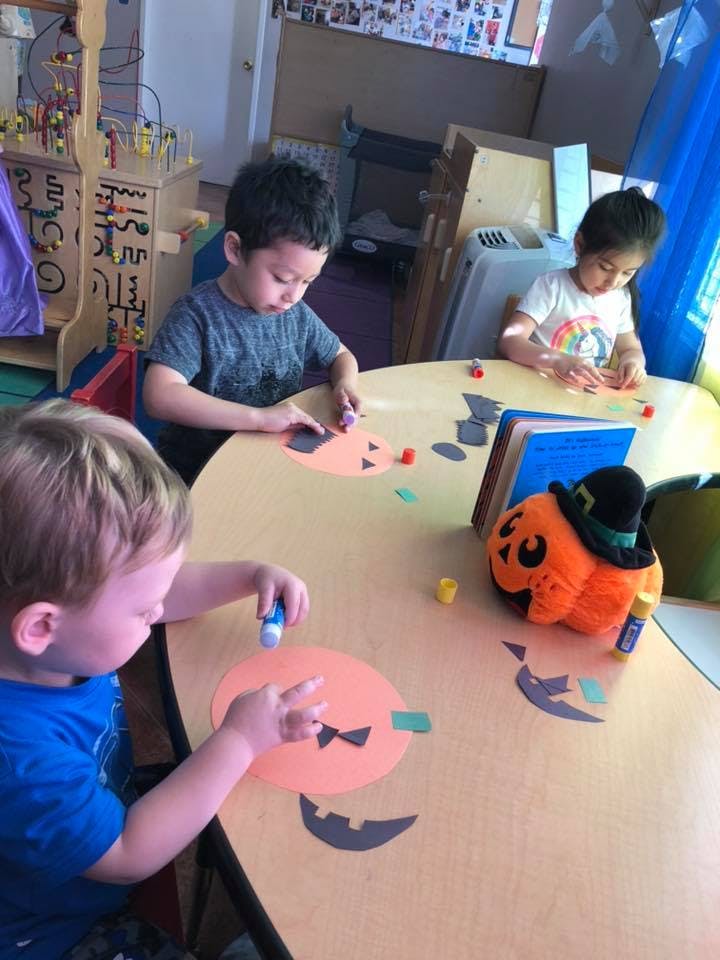 Three children sitting at a table doing crafts