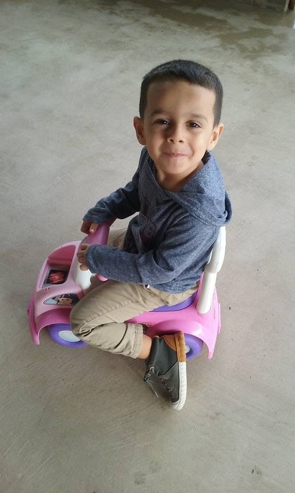 Child sitting on a pink toy car