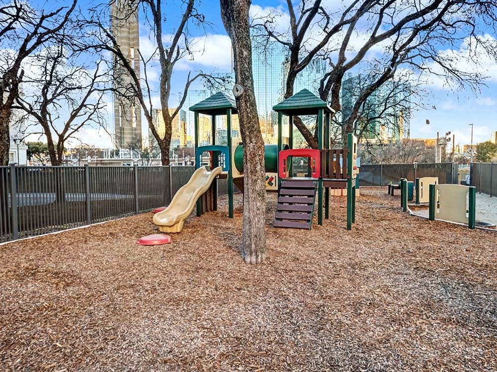 Empty children's playground with slide and climbing structure on wood chips