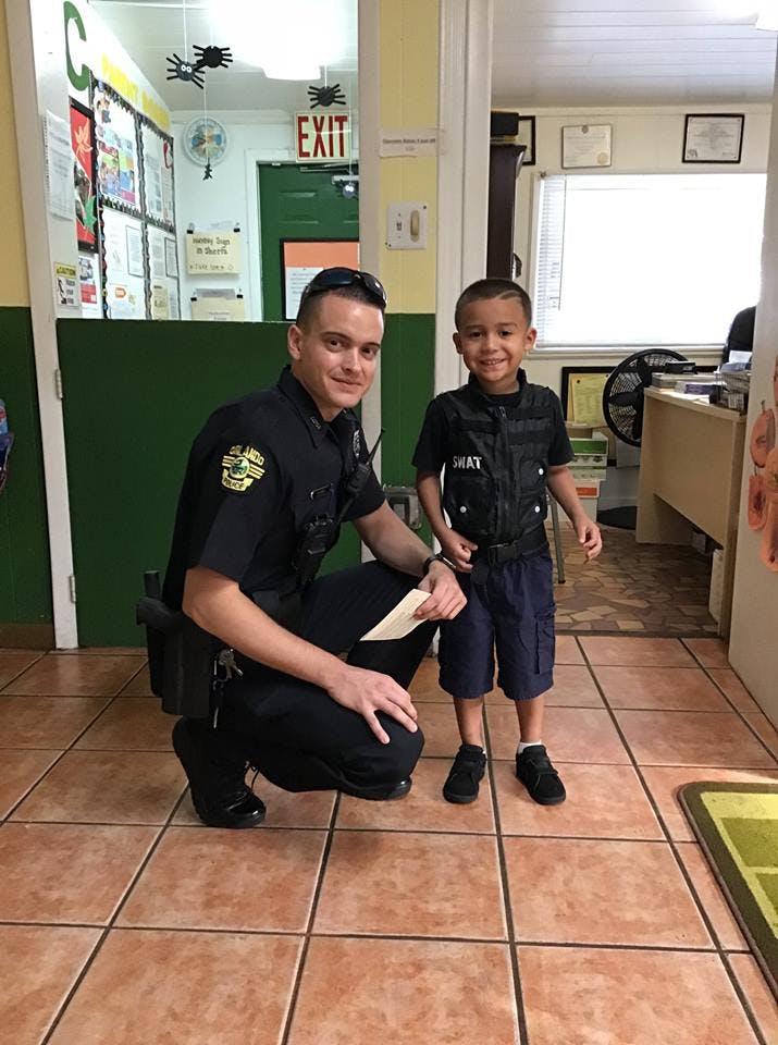 Adult in uniform kneeling next to a child