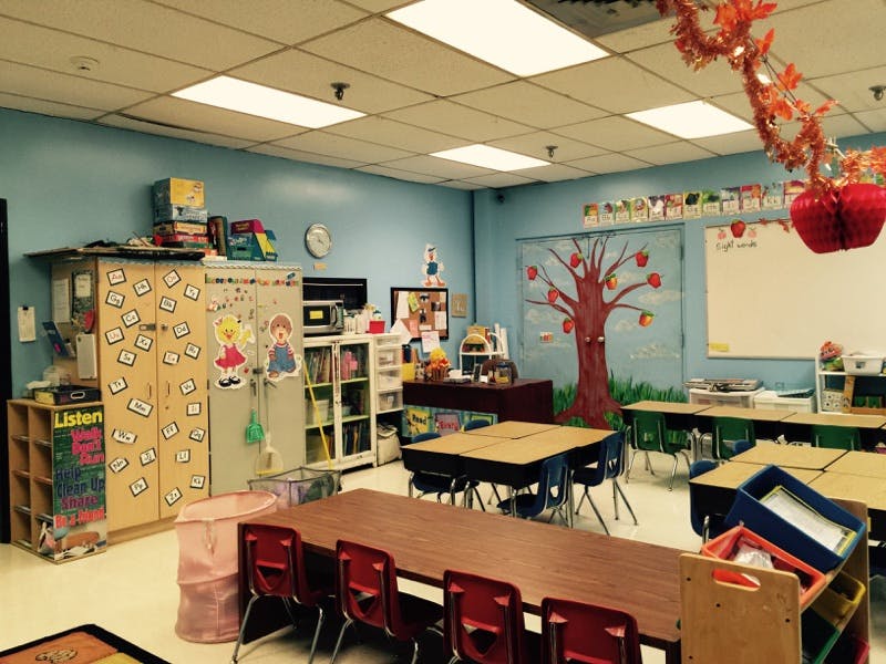 Classroom with tables and chairs, decorated with an apple tree cutout