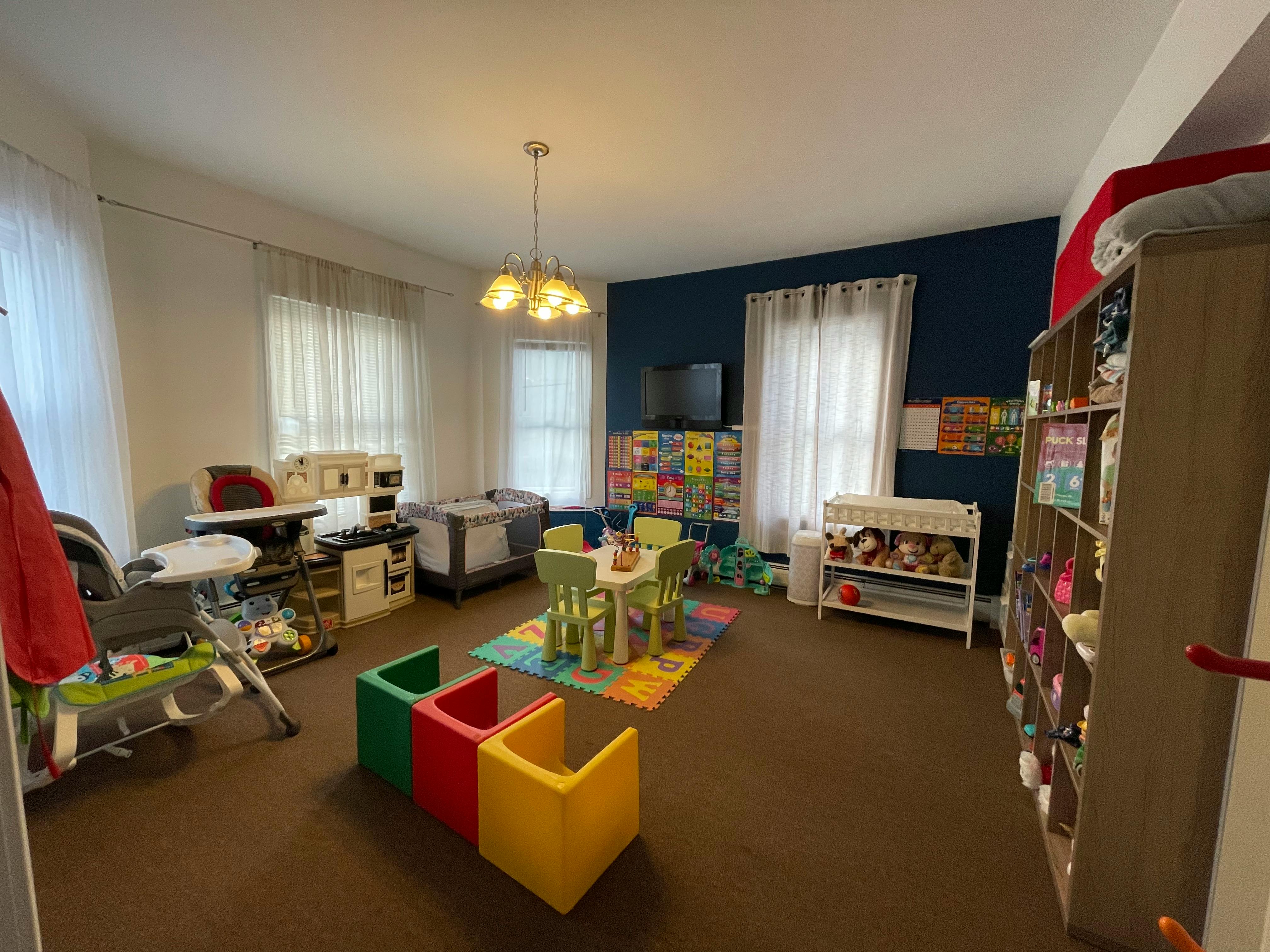 Playroom with small table and chairs, colorful rug, and toy storage