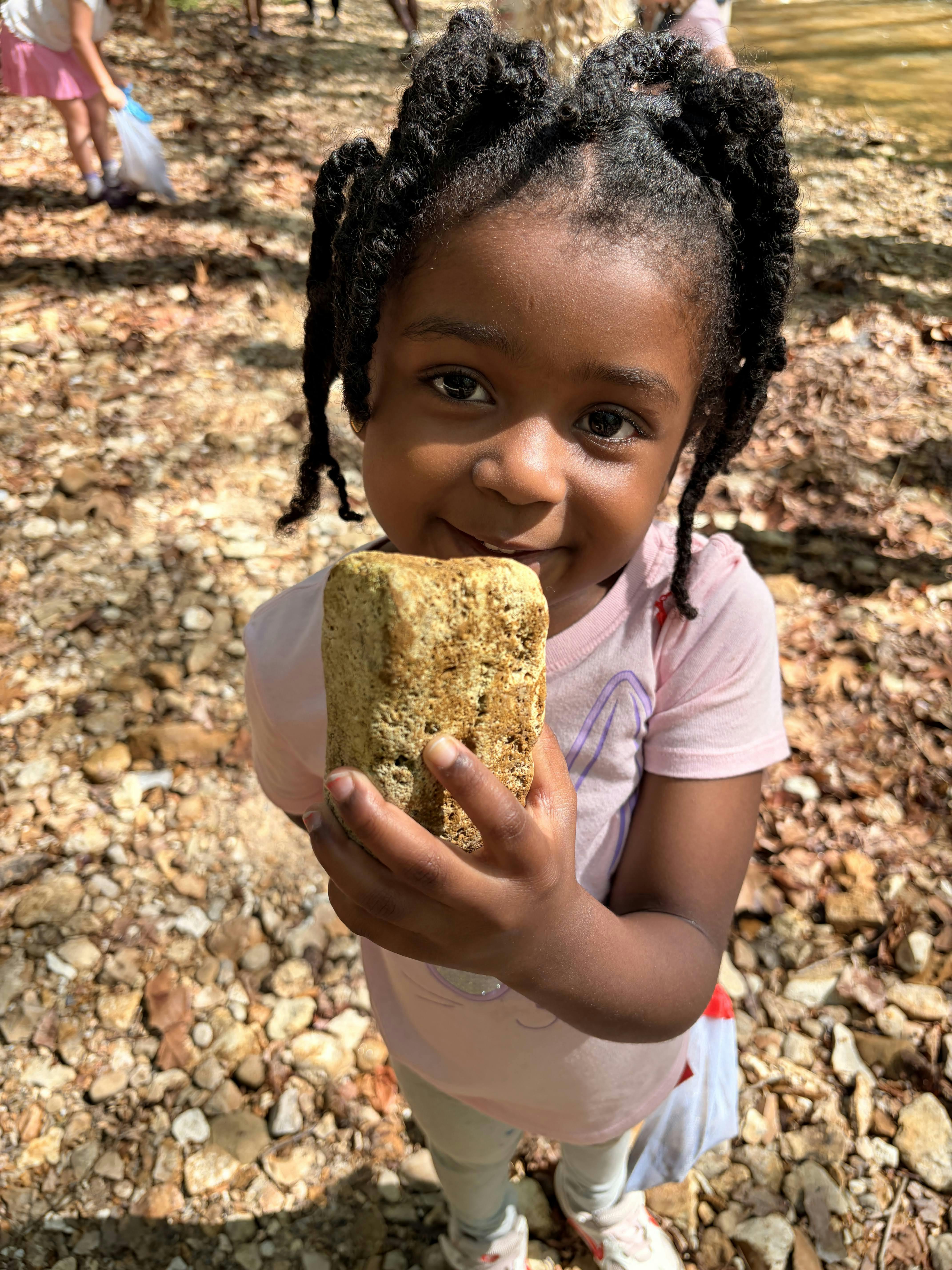 Child holding a rock outdoors