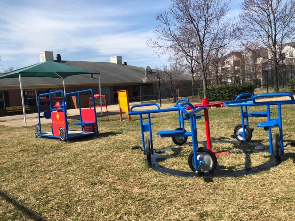 Playground with a blue and red play structure and a merry-go-round