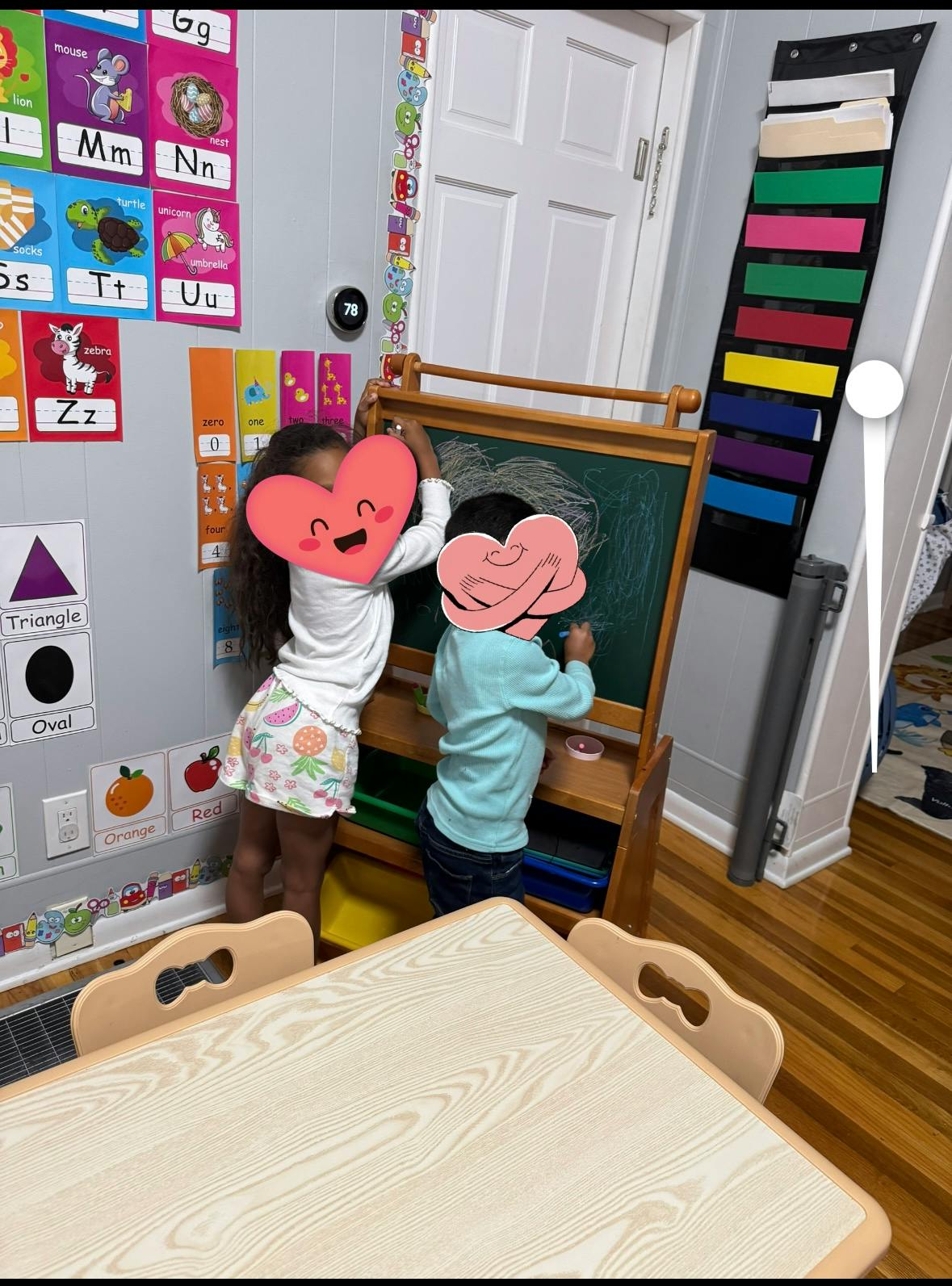 Two children drawing on a chalkboard in a classroom