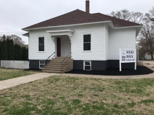 White house with a brown roof and a sign that says "Solid Rock"