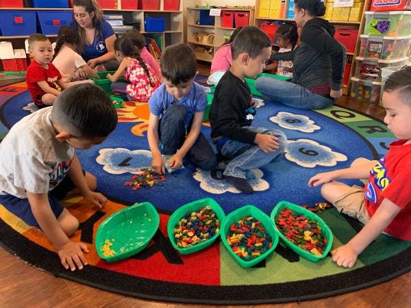 Children playing with colorful blocks on a rug in a classroom