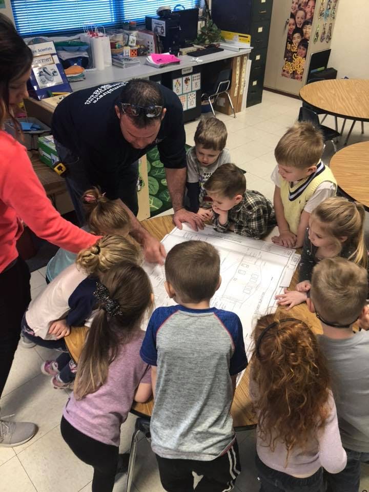 Adults and children gathered around a table looking at a large document