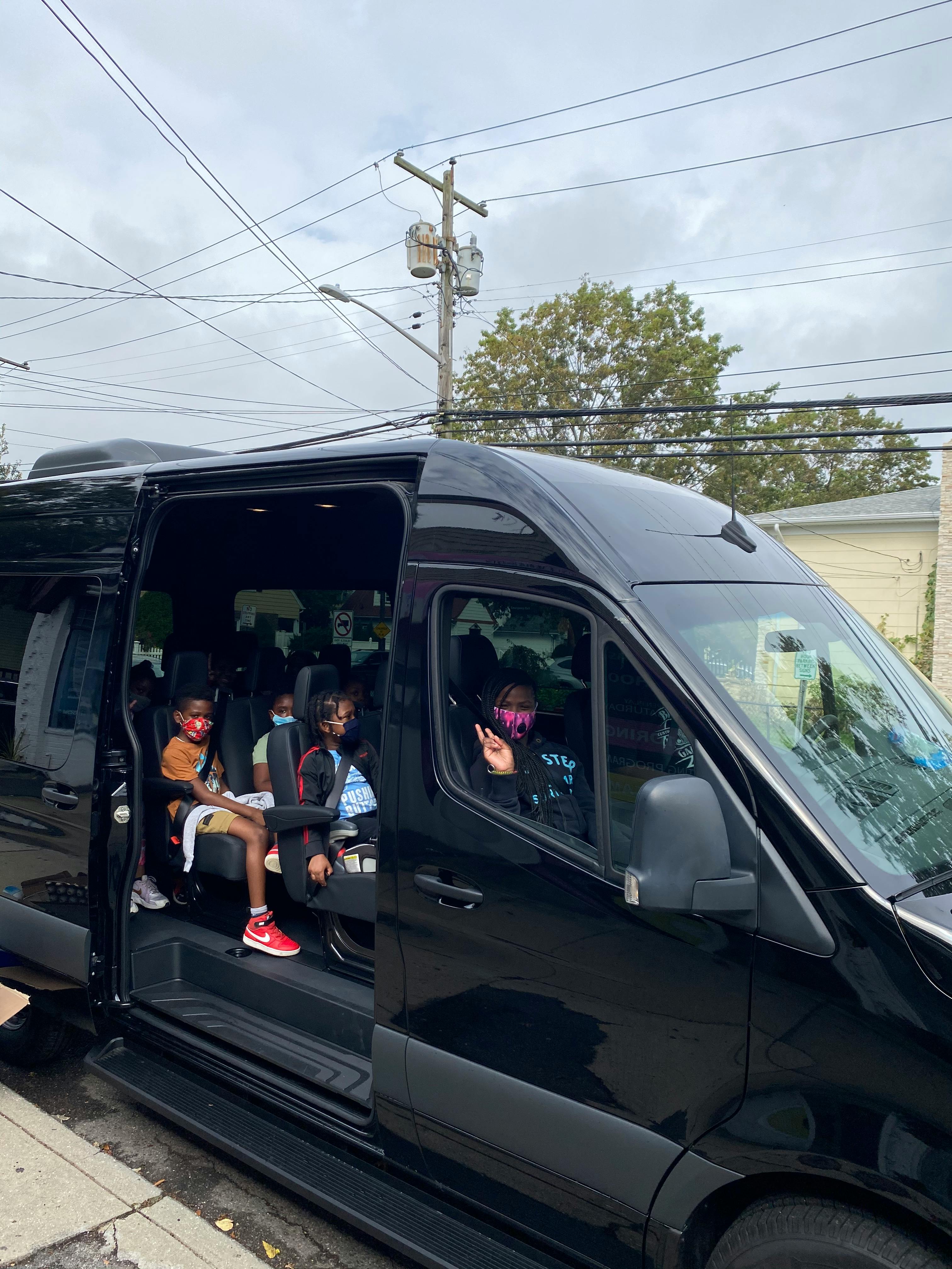 Children in a black van, one person making a peace sign