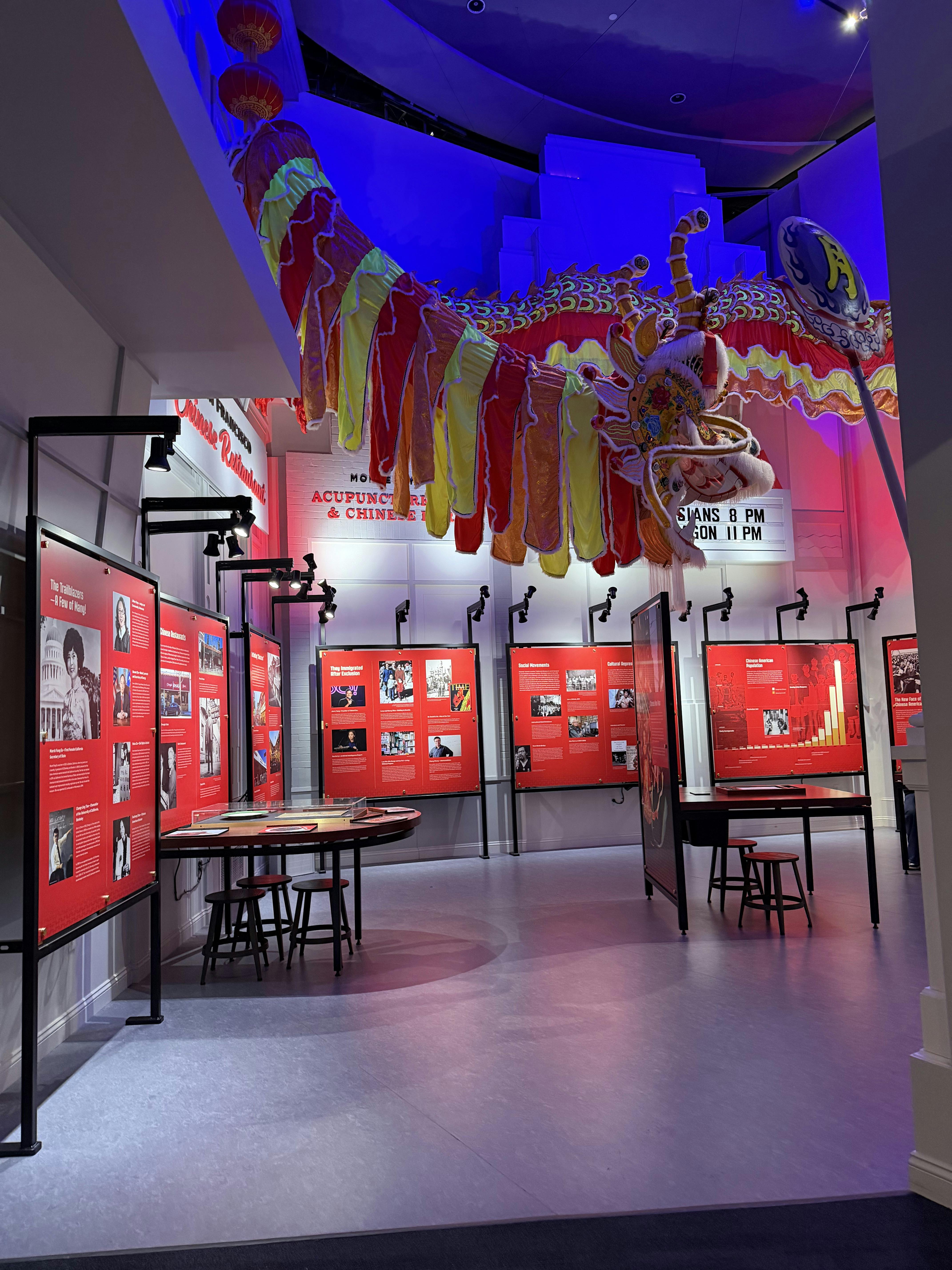 Museum exhibit with large red and yellow dragon hanging from ceiling, information panels