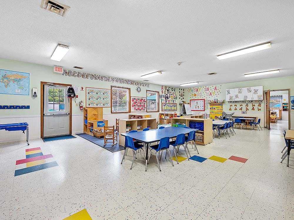 Empty classroom with small blue tables and chairs