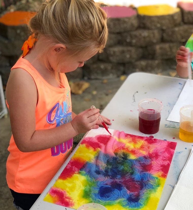 Child painting a colorful abstract design on paper