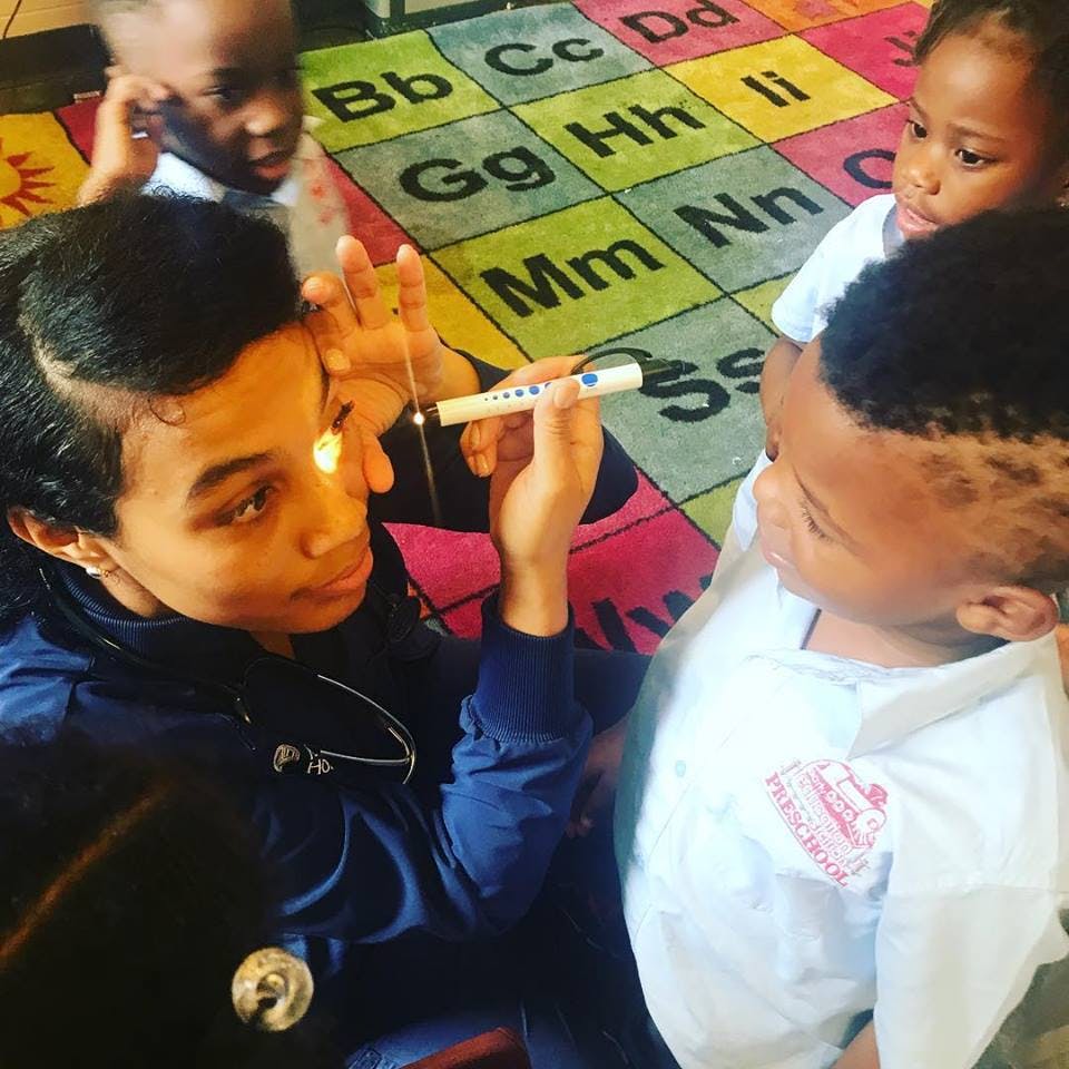 Teen holding a penlight to a child's eye