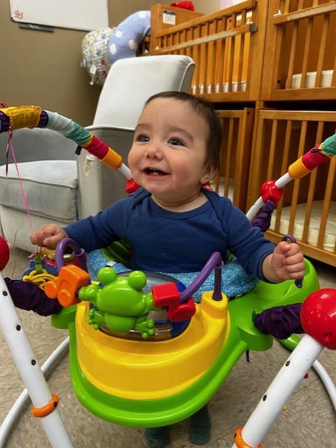 Child in a colorful baby bouncer with toys