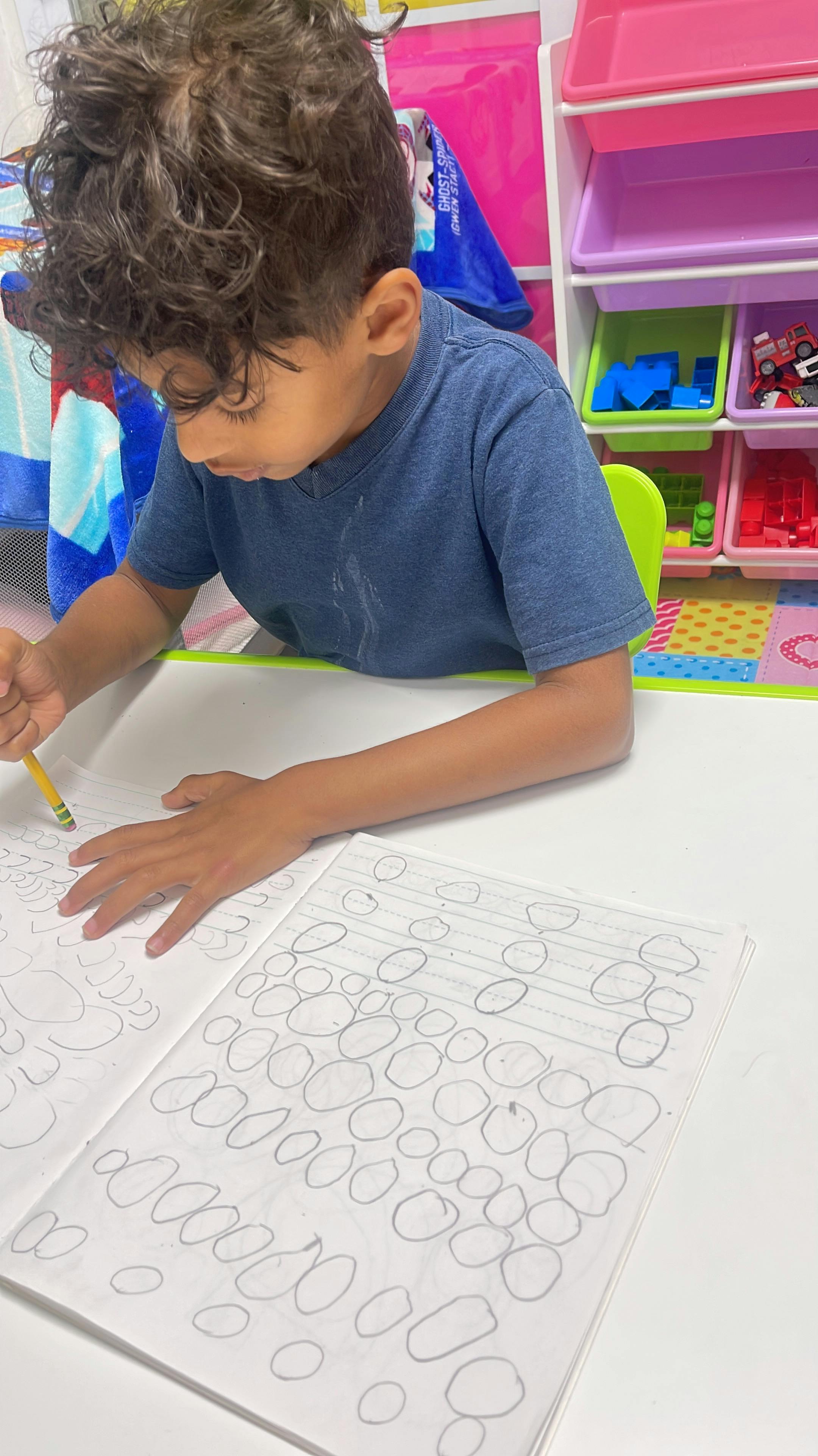Child drawing with a pencil in a notebook
