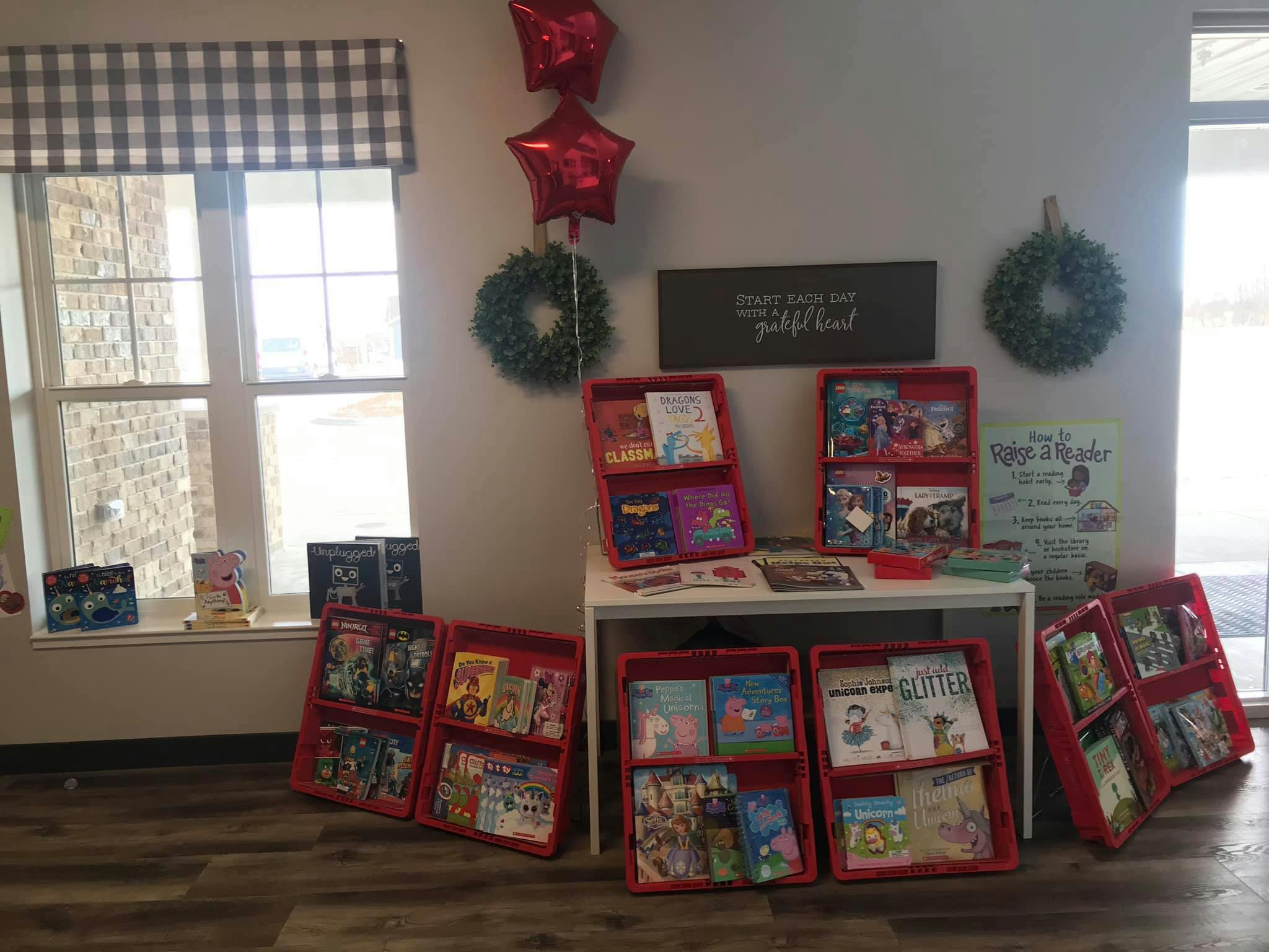Red book displays with books in a room with windows and holiday decorations