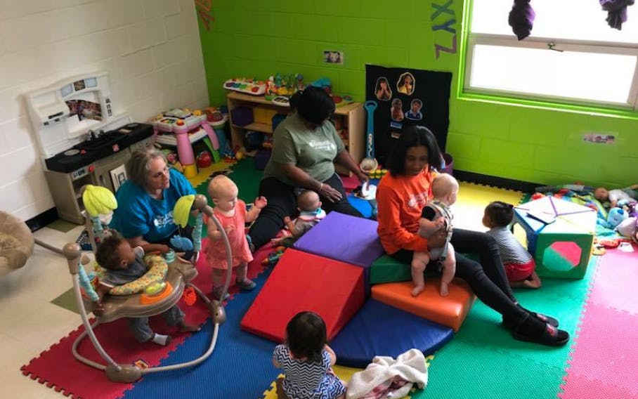 Adults and children playing in a room with colorful mats and soft play equipment