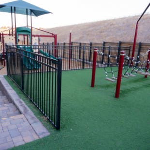 Playground with green turf and black fence