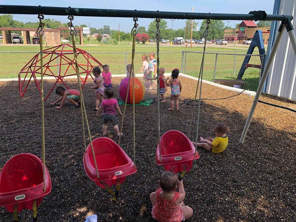 Children playing on a playground with swings and a climbing dome