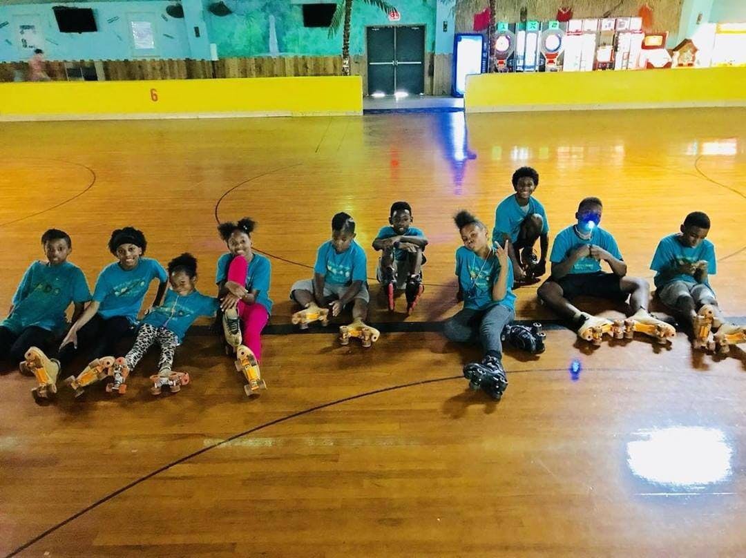Group of people sitting on a roller skating rink floor