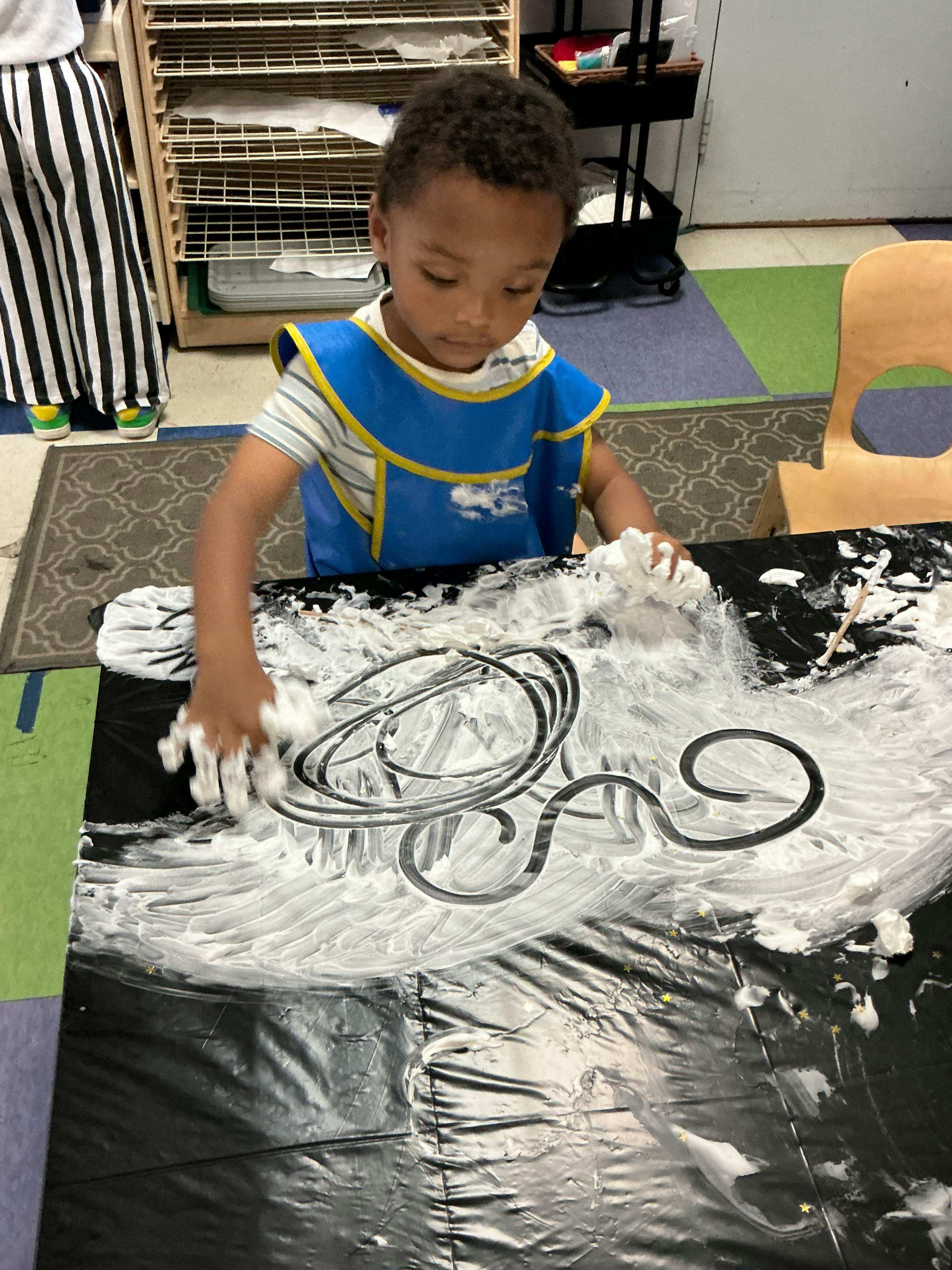 Child playing with shaving cream on a black tabletop