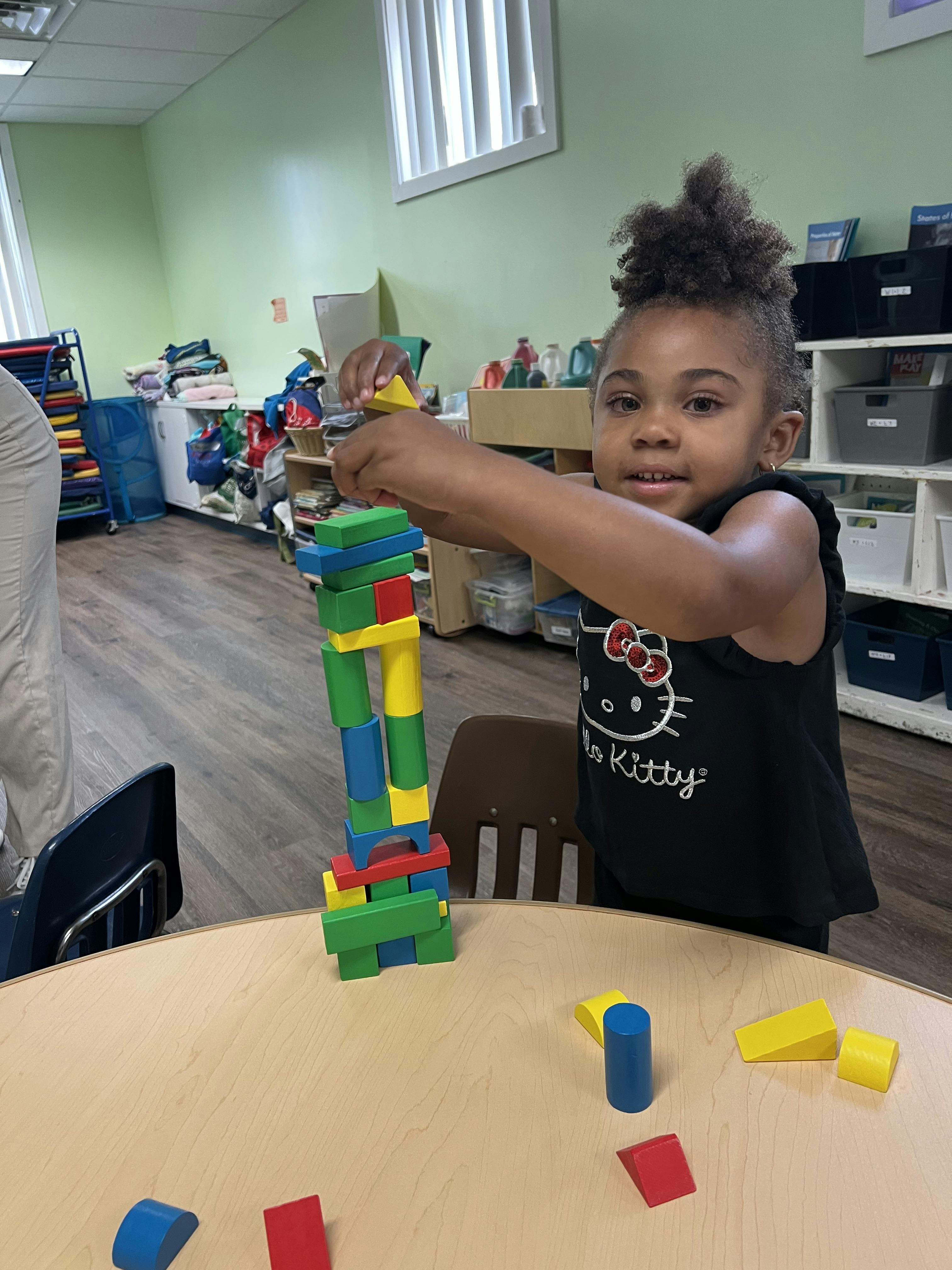 Child building a tower with colorful blocks on a table