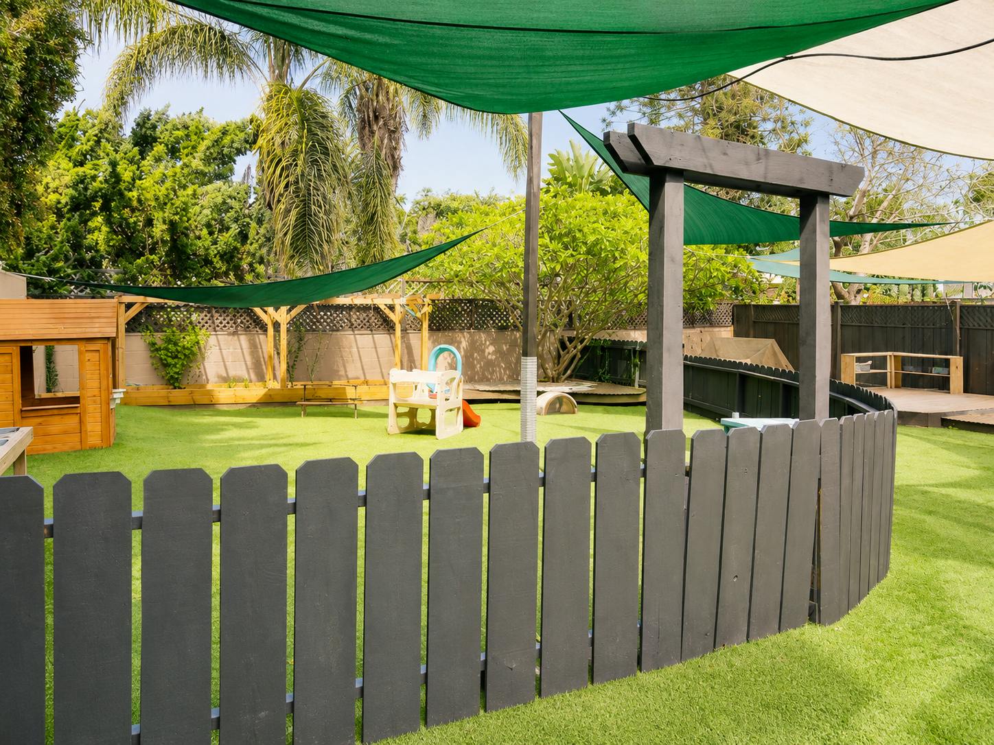 Backyard playground with artificial turf and shade sails