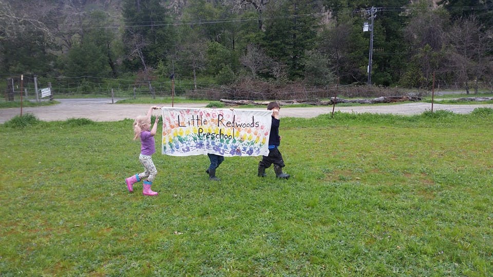 Two children carrying a banner across a grassy field