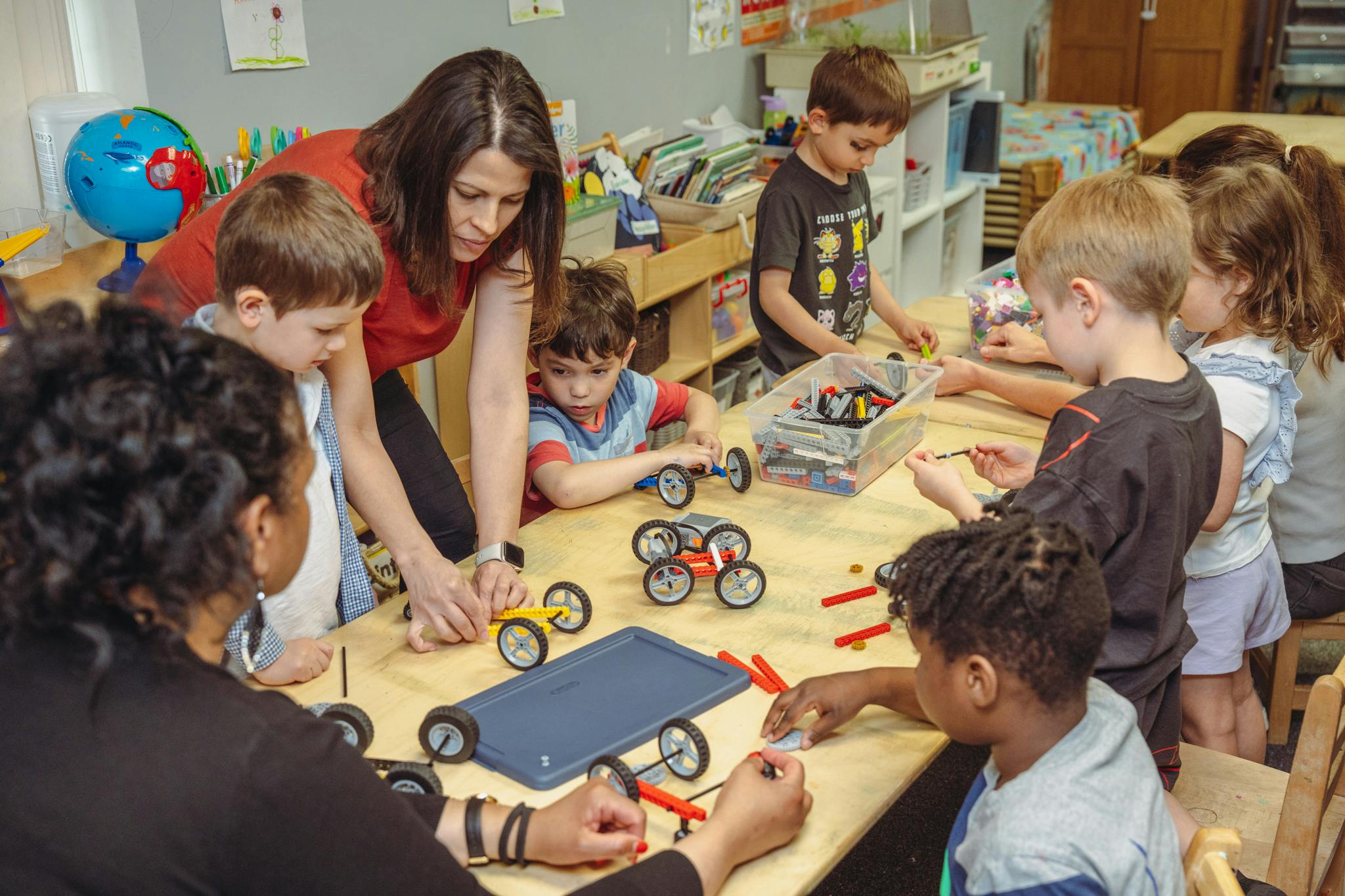 Adults and children building toy cars at a table