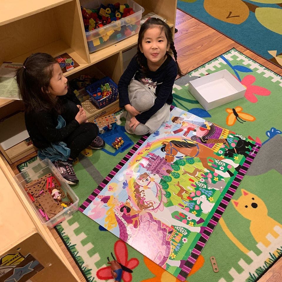 Two children on a rug with a large puzzle