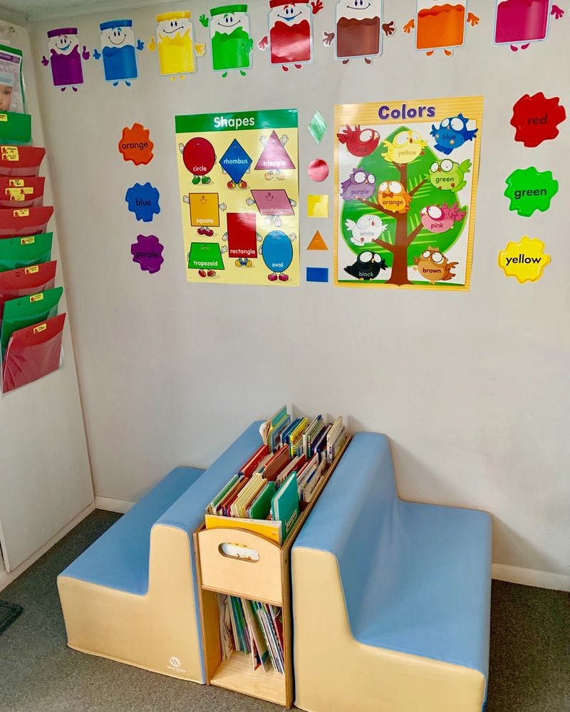 Classroom corner with a small bookshelf and educational posters on the wall