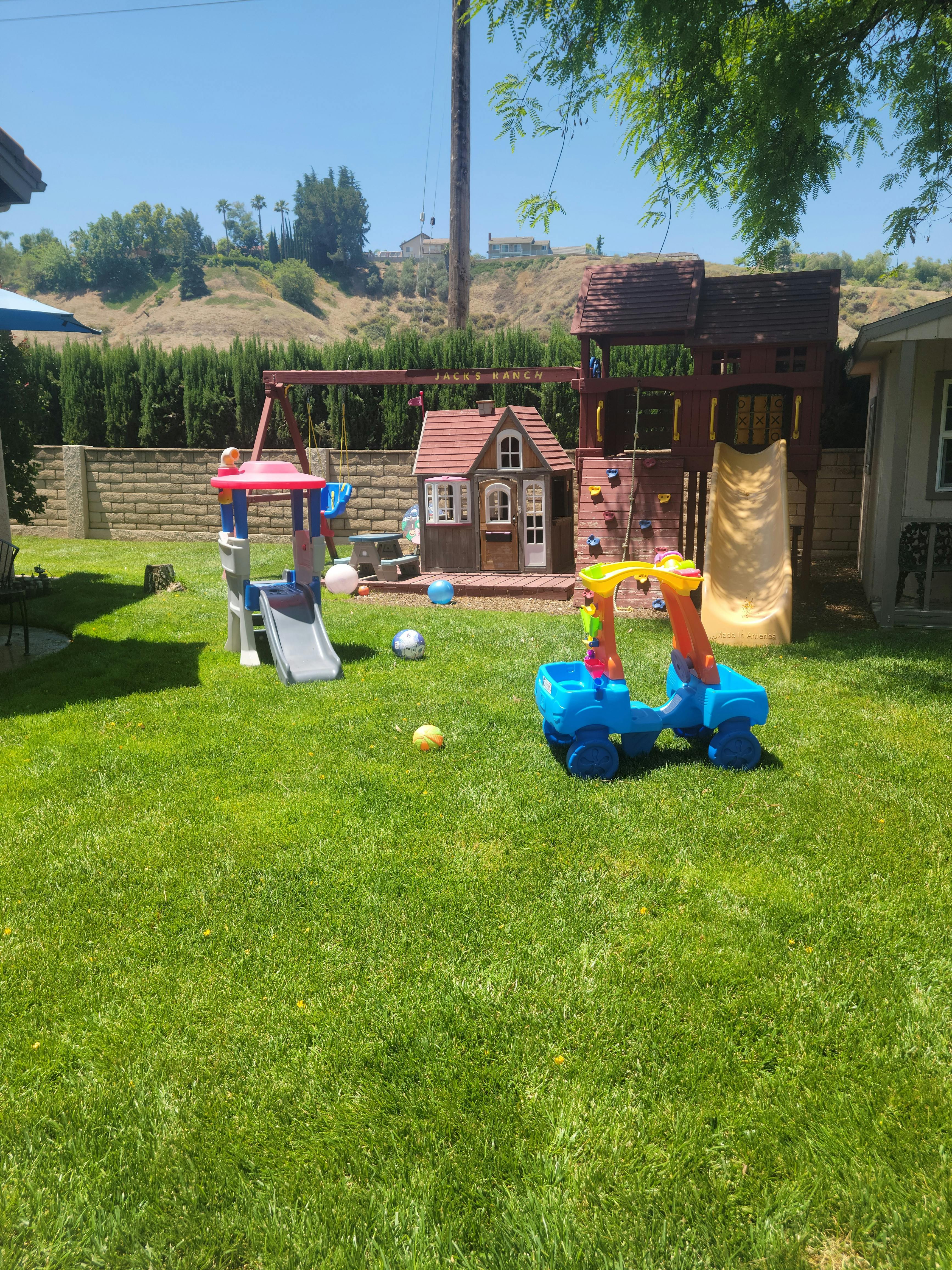Backyard with a wooden playset, a small playhouse, and a plastic slide