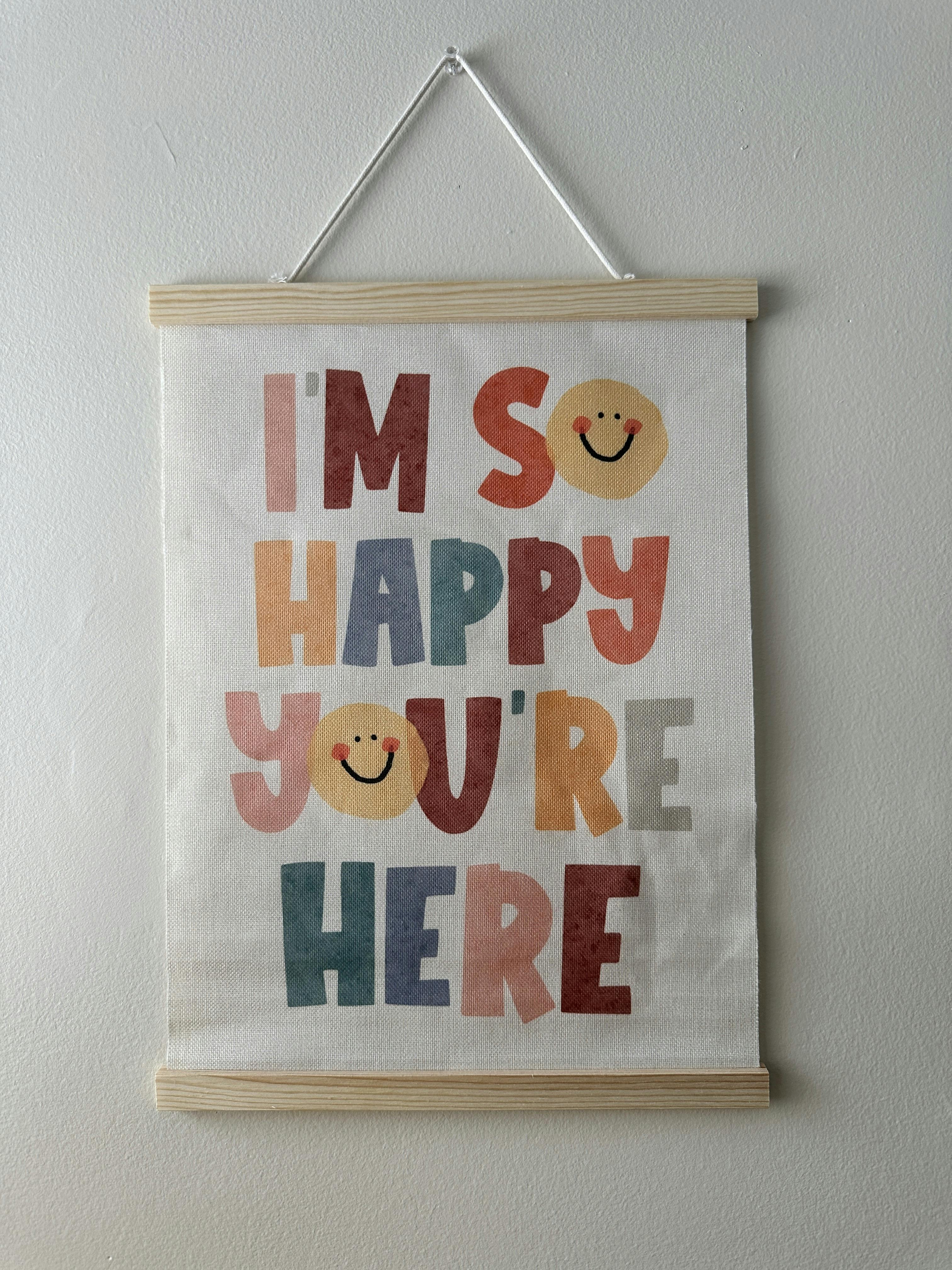 Wall hanging with the text I am so happy you are here and smiley face icons