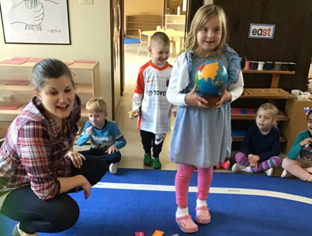 Adult and children in a classroom, one child holding a globe
