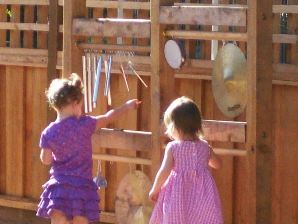 Child playing with chimes and another child watching