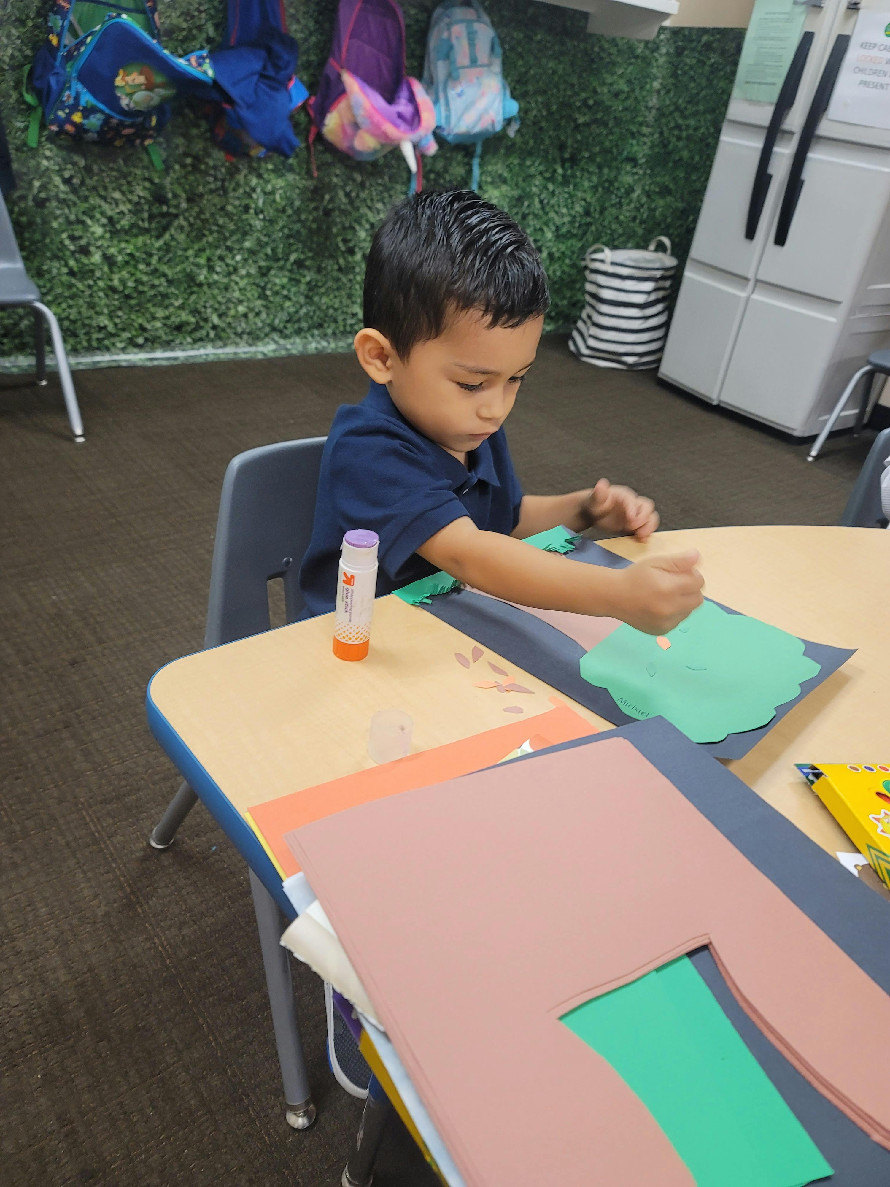 Child at a table doing a craft with paper and glue