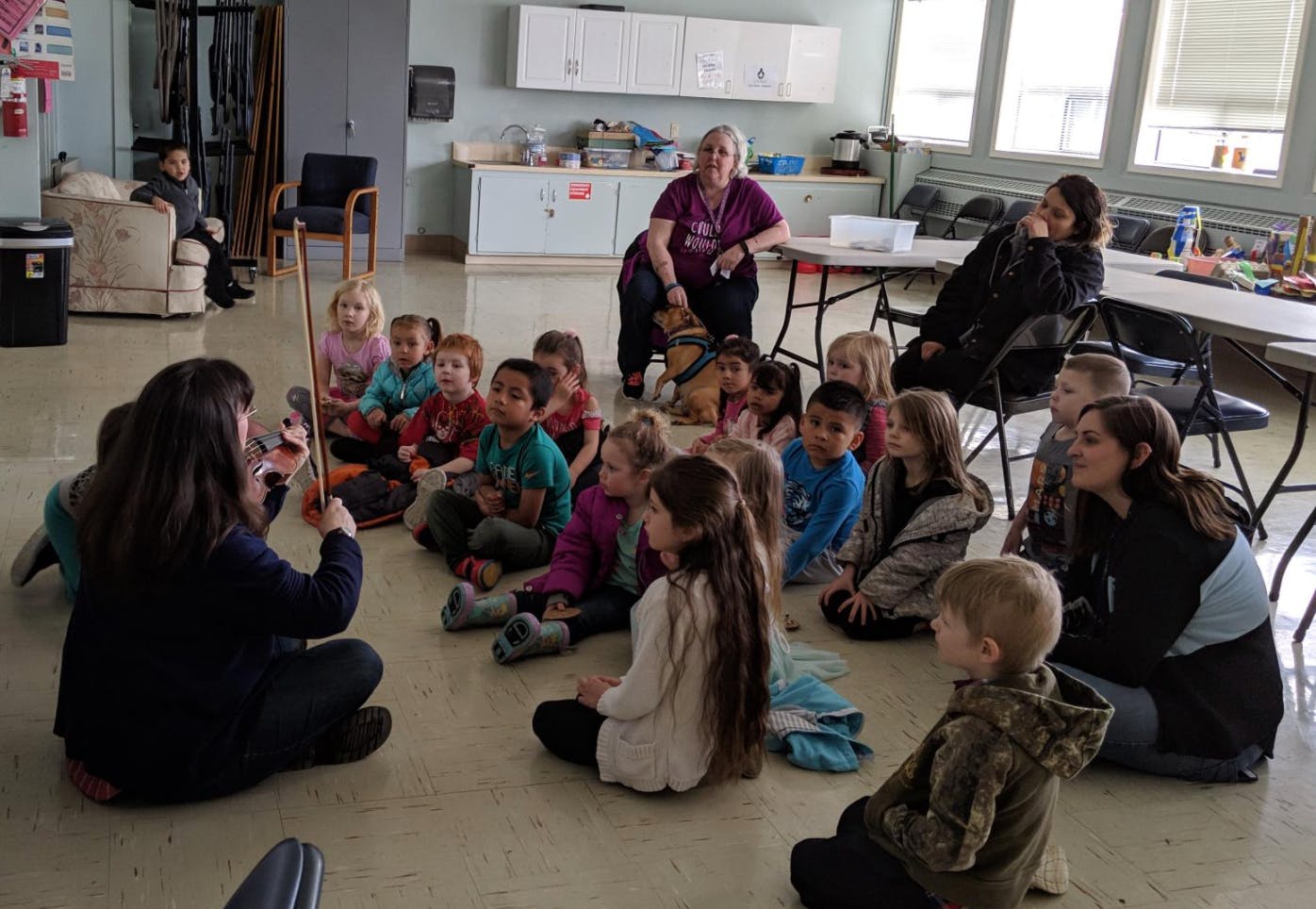 Person playing a string instrument for a group of children and adults