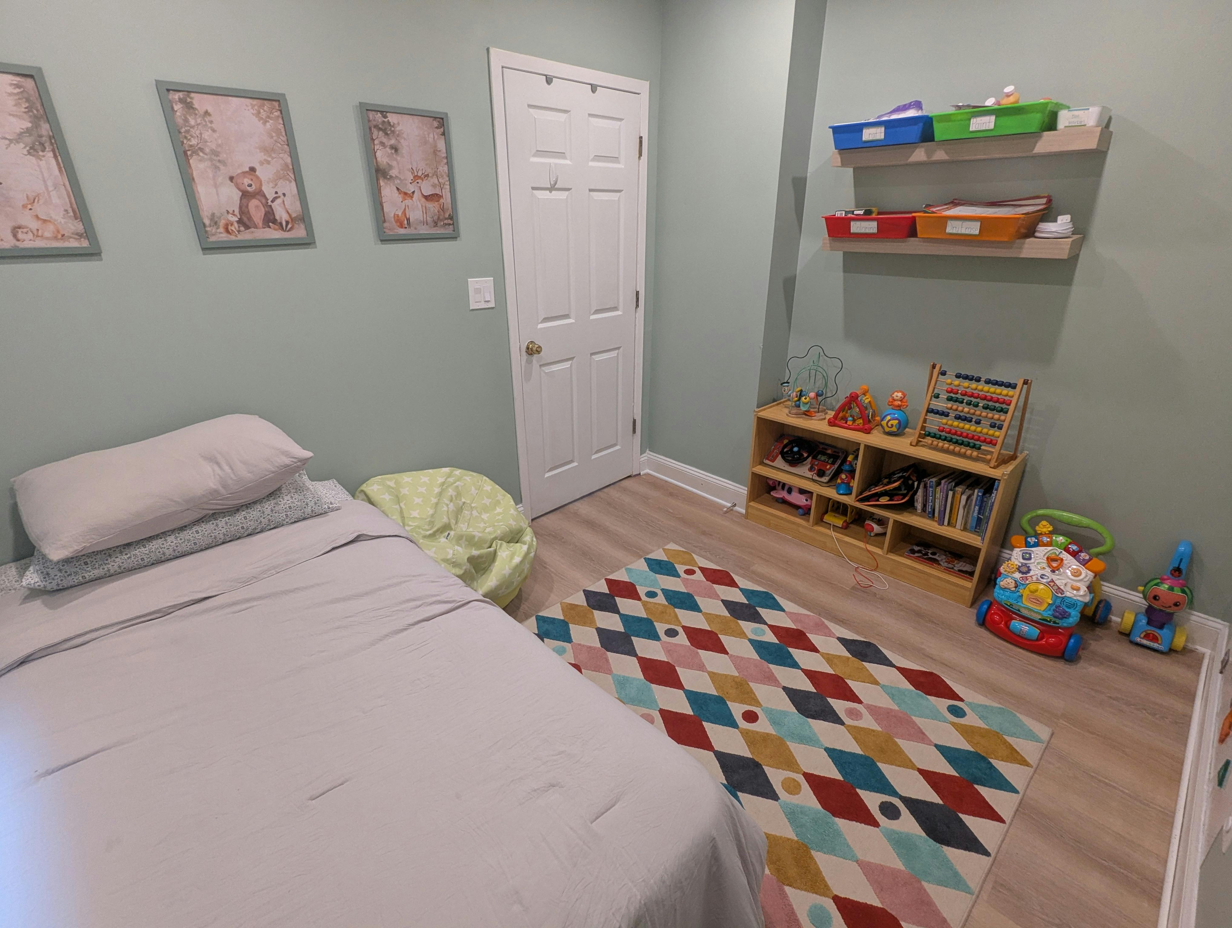 Child's bedroom with a bed, colorful rug, shelves, and toys
