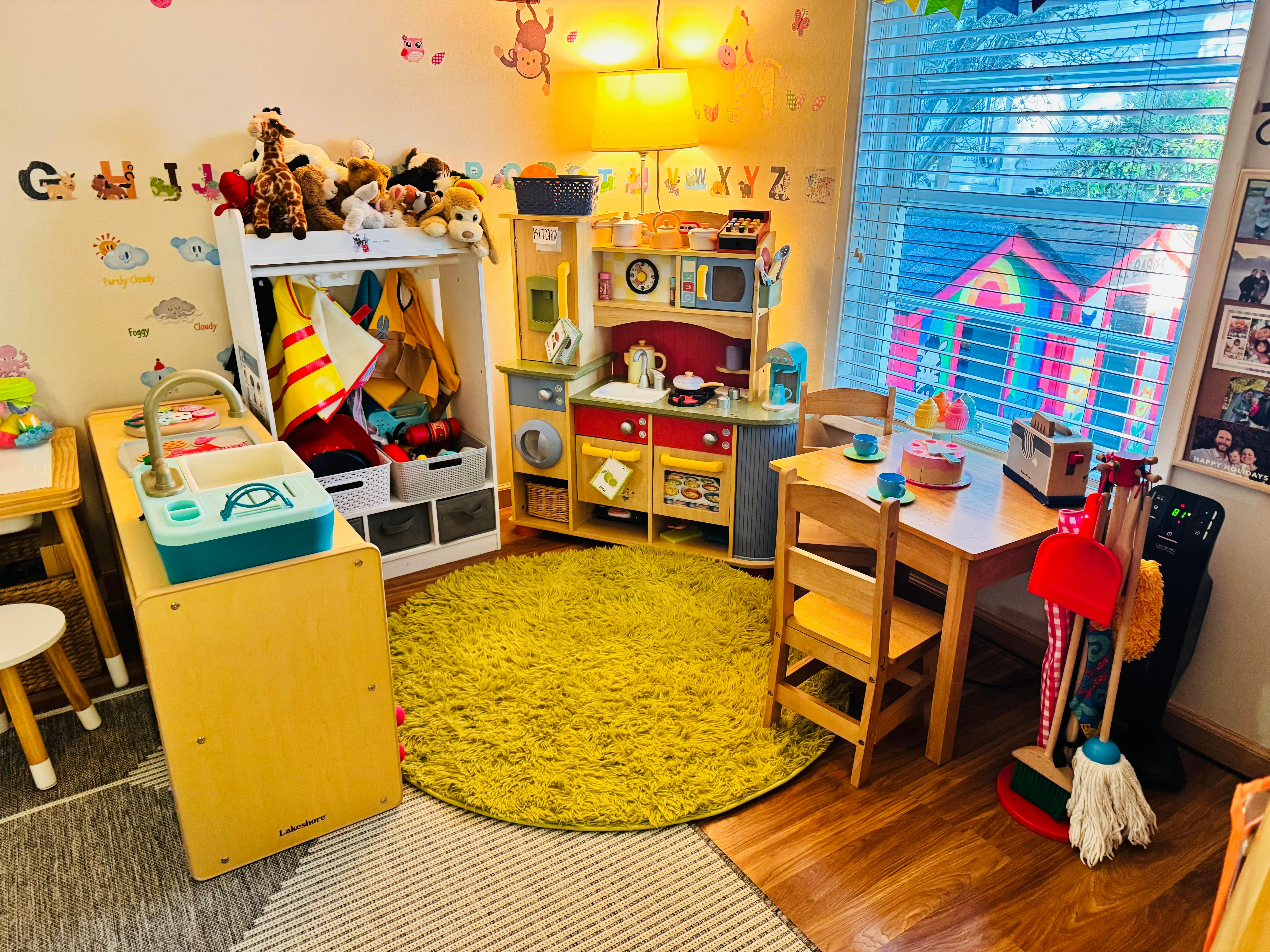 Playroom with a toy kitchen, small table and chairs, and a green rug