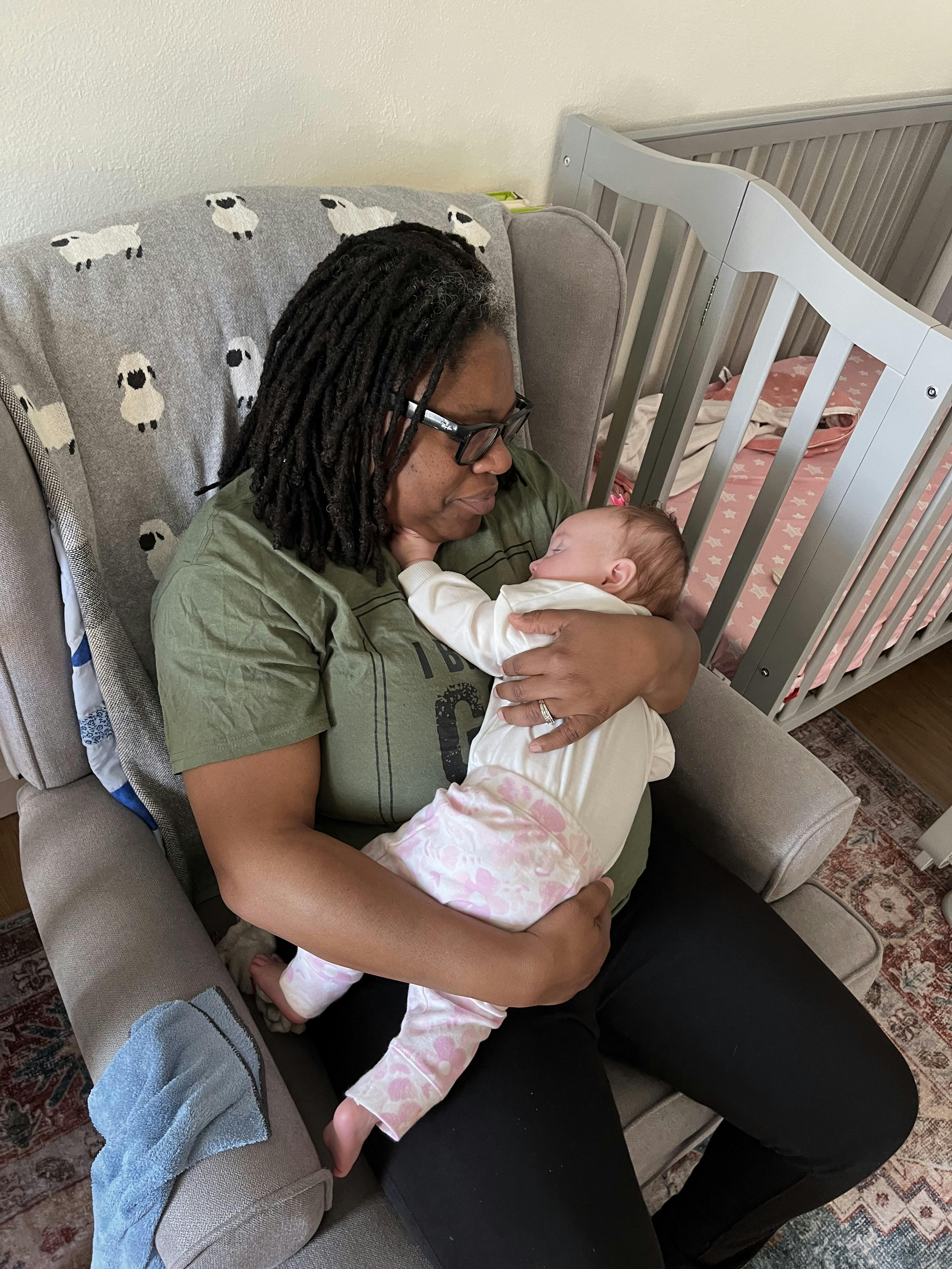 Person holding a sleeping child in a chair