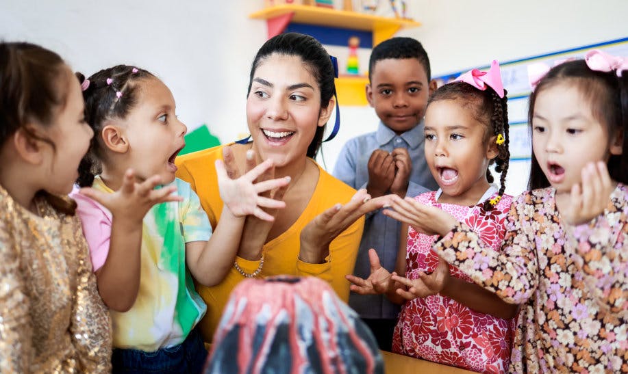 Adult and children gathered around a model volcano in a classroom