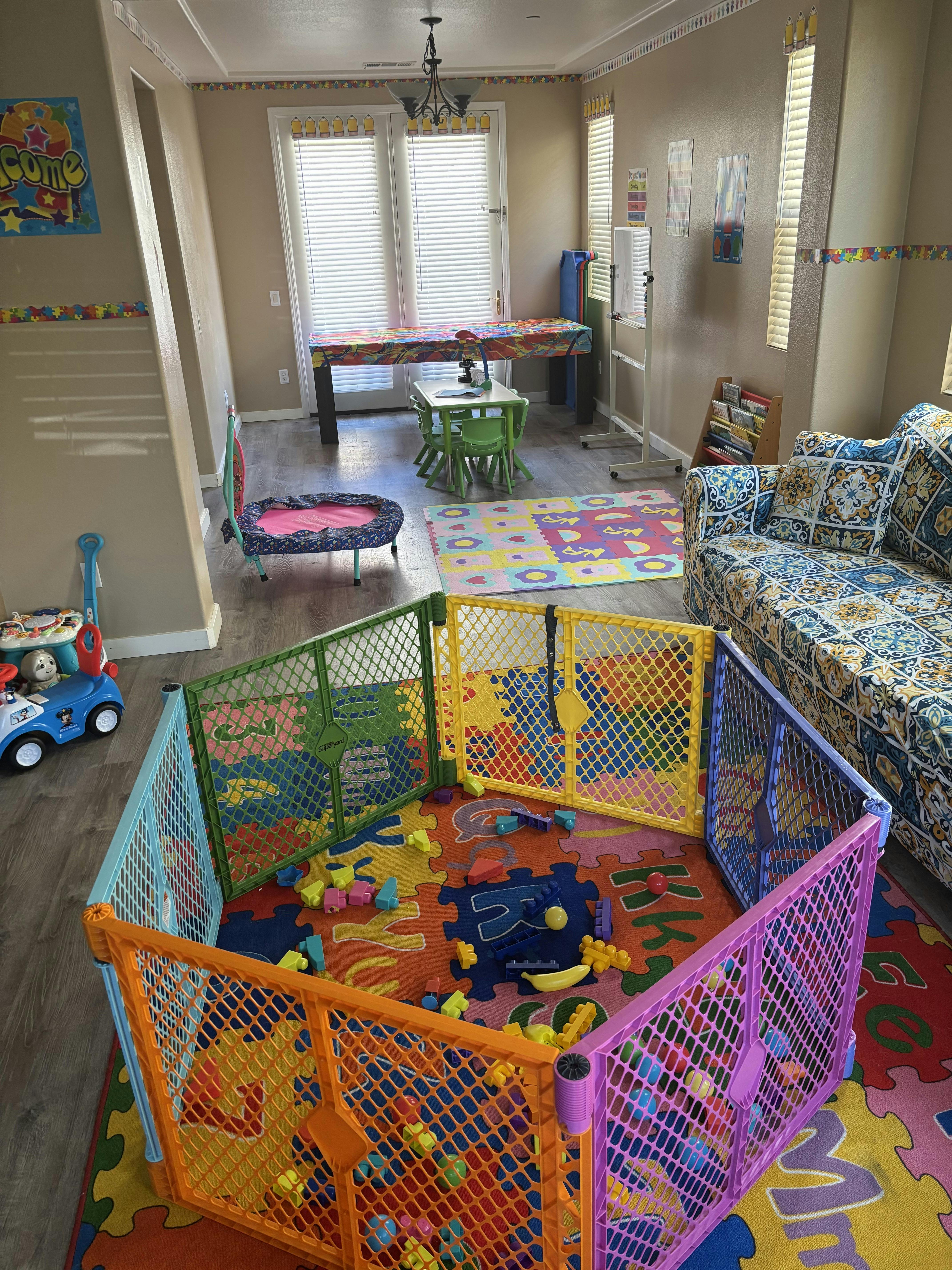 Child's play area with colorful floor mat, playpen, and toys