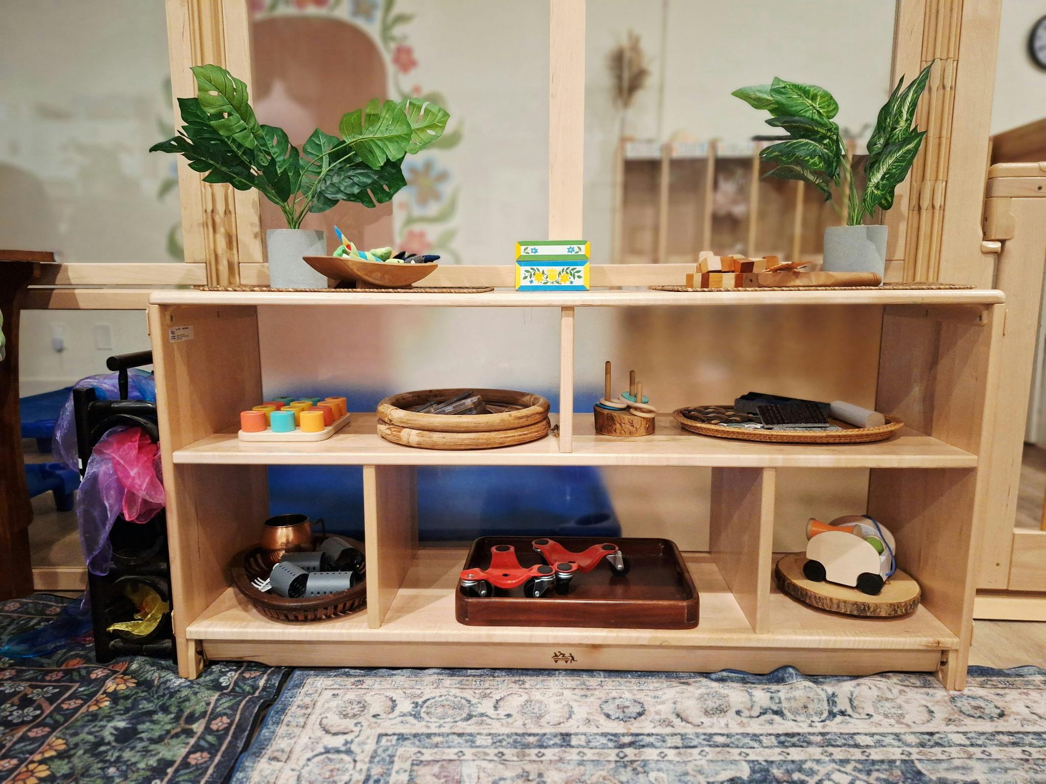 Wooden shelving unit stocked with various educational toys and trays