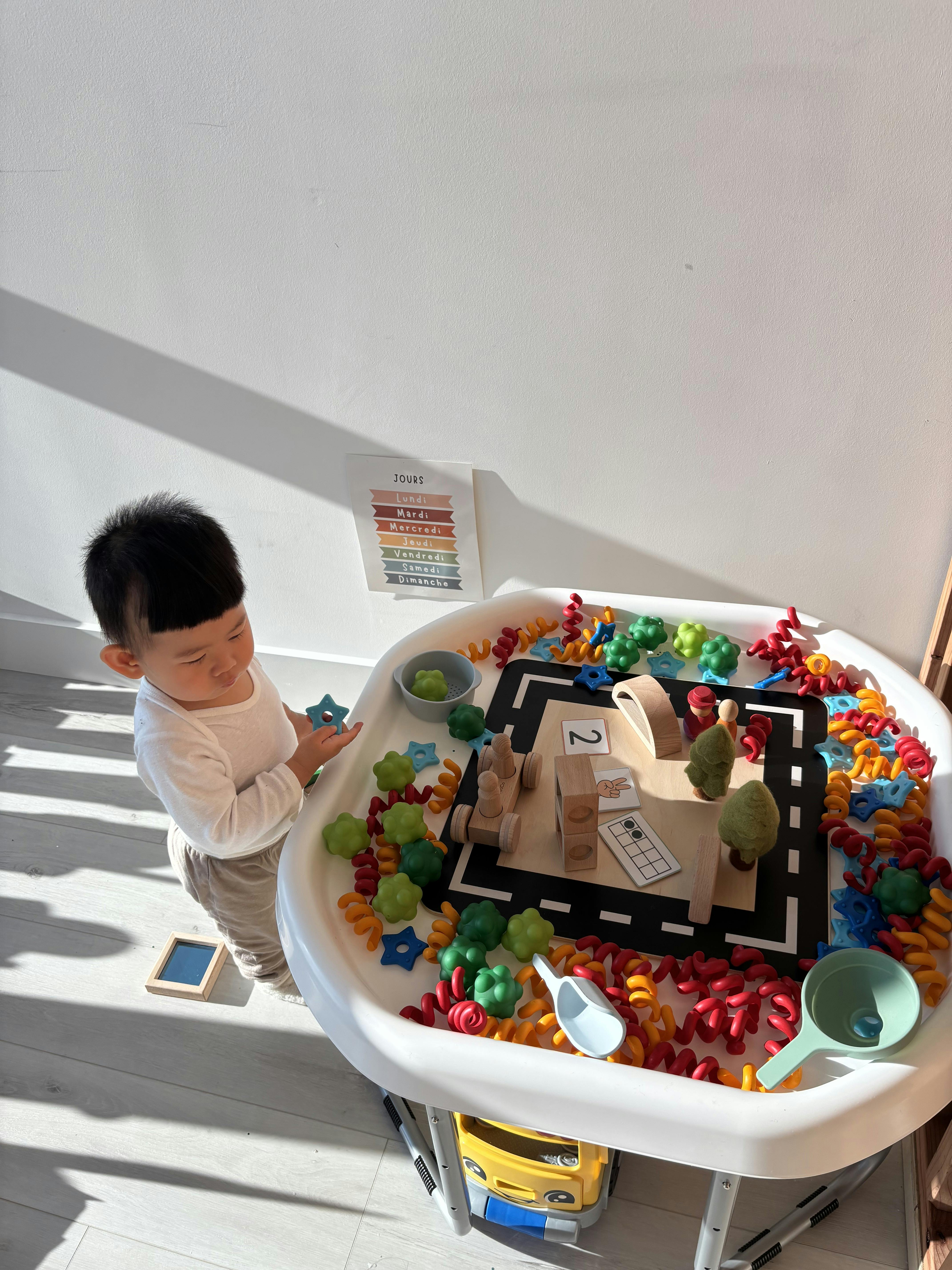 Child playing with toys on a sensory table